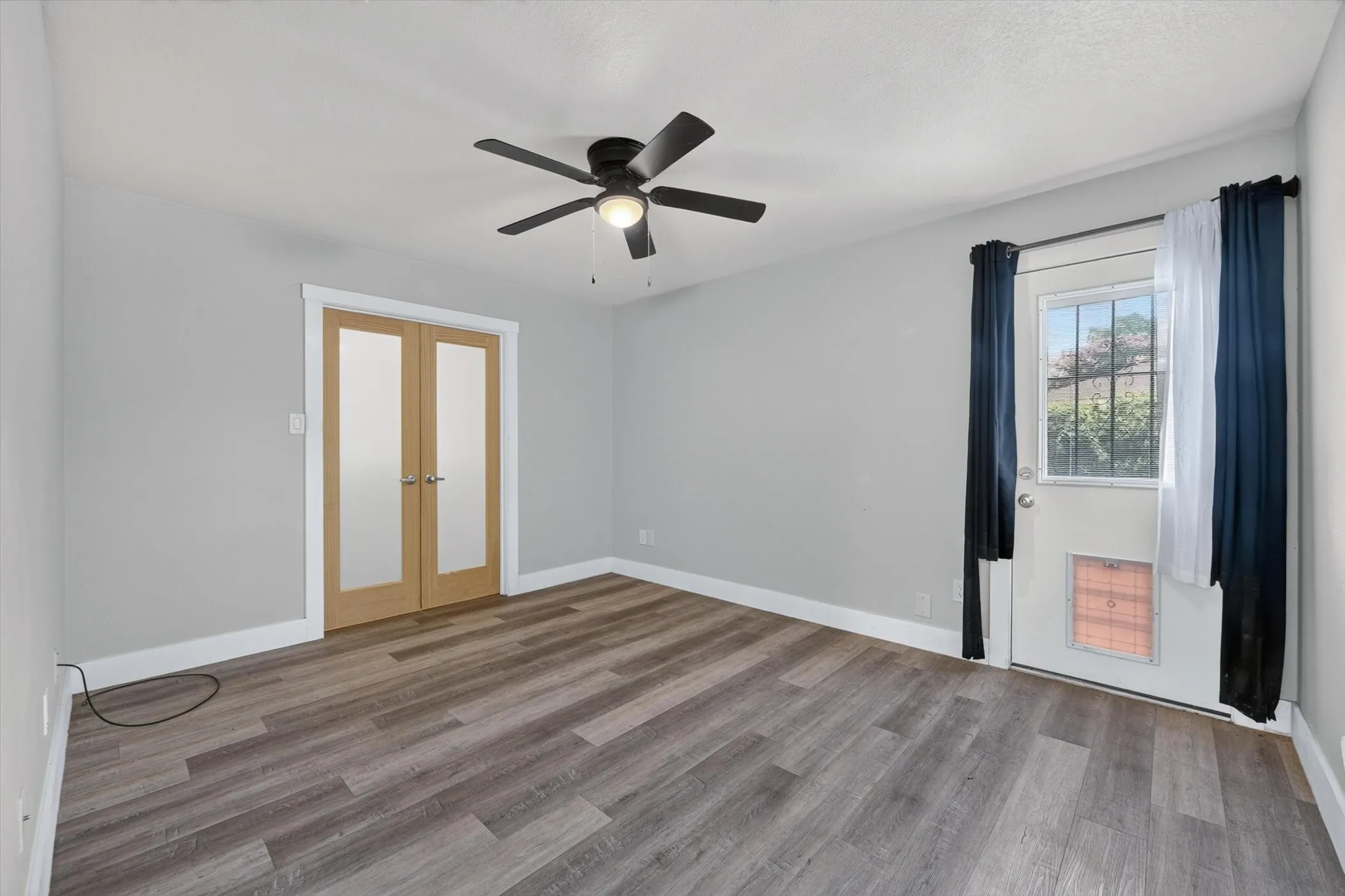 Interior space featuring wood-finish flooring, light gray wall paint, and white baseboards