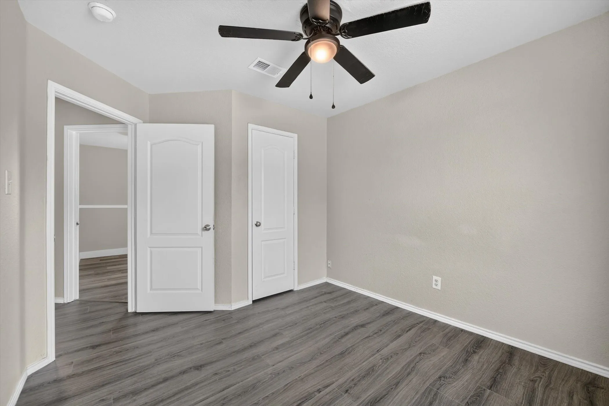 Room featuring wood-finish flooring, light neutral wall tones, and white baseboards