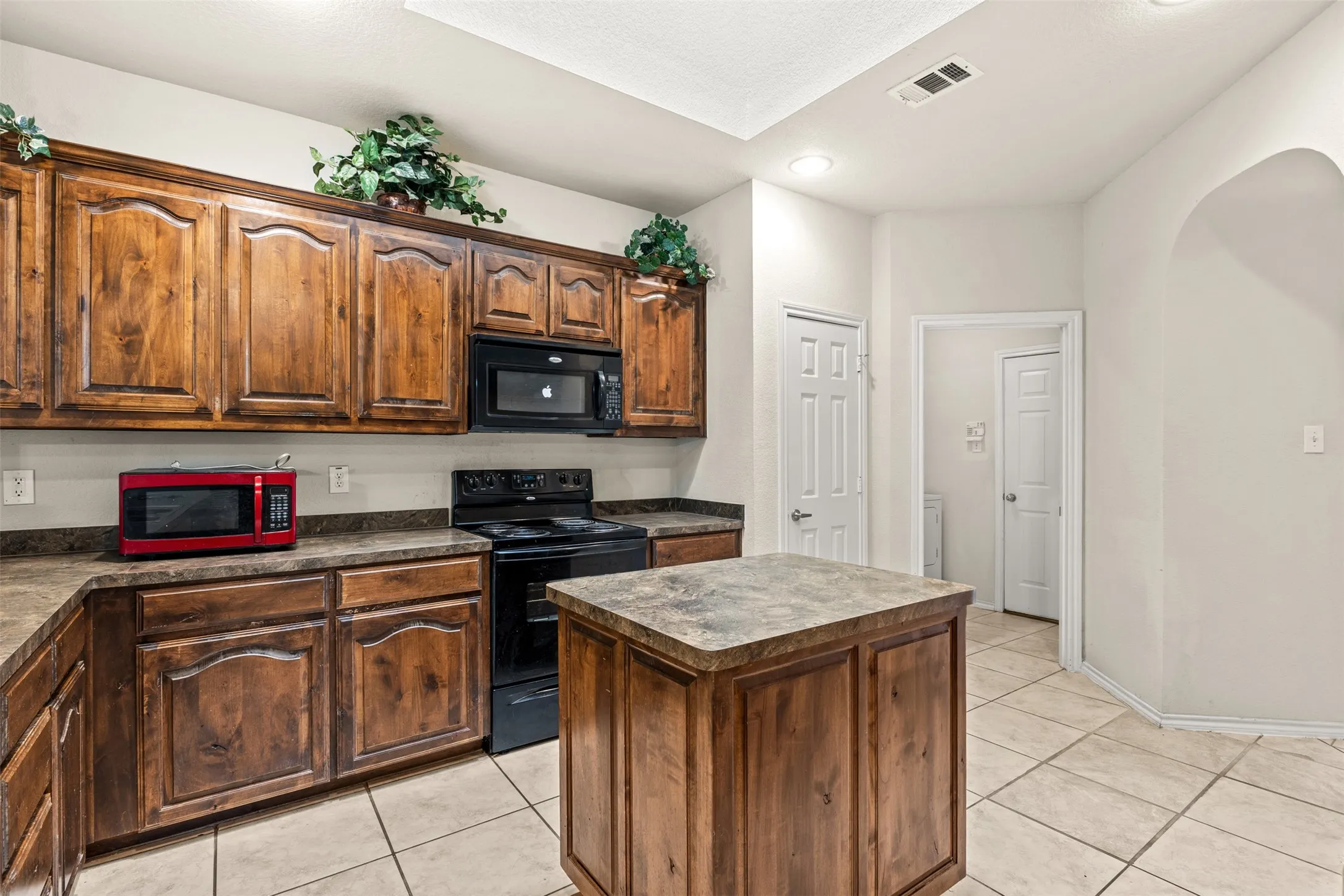 Kitchen featuring abundant wood-finish cabinetry, black electric range, and a built-in microwave
