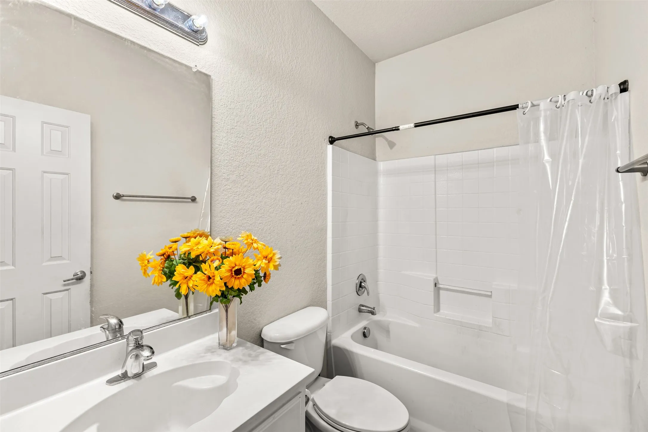 Bathroom featuring a white vanity with integrated sink, chrome faucet, and full-width mirror