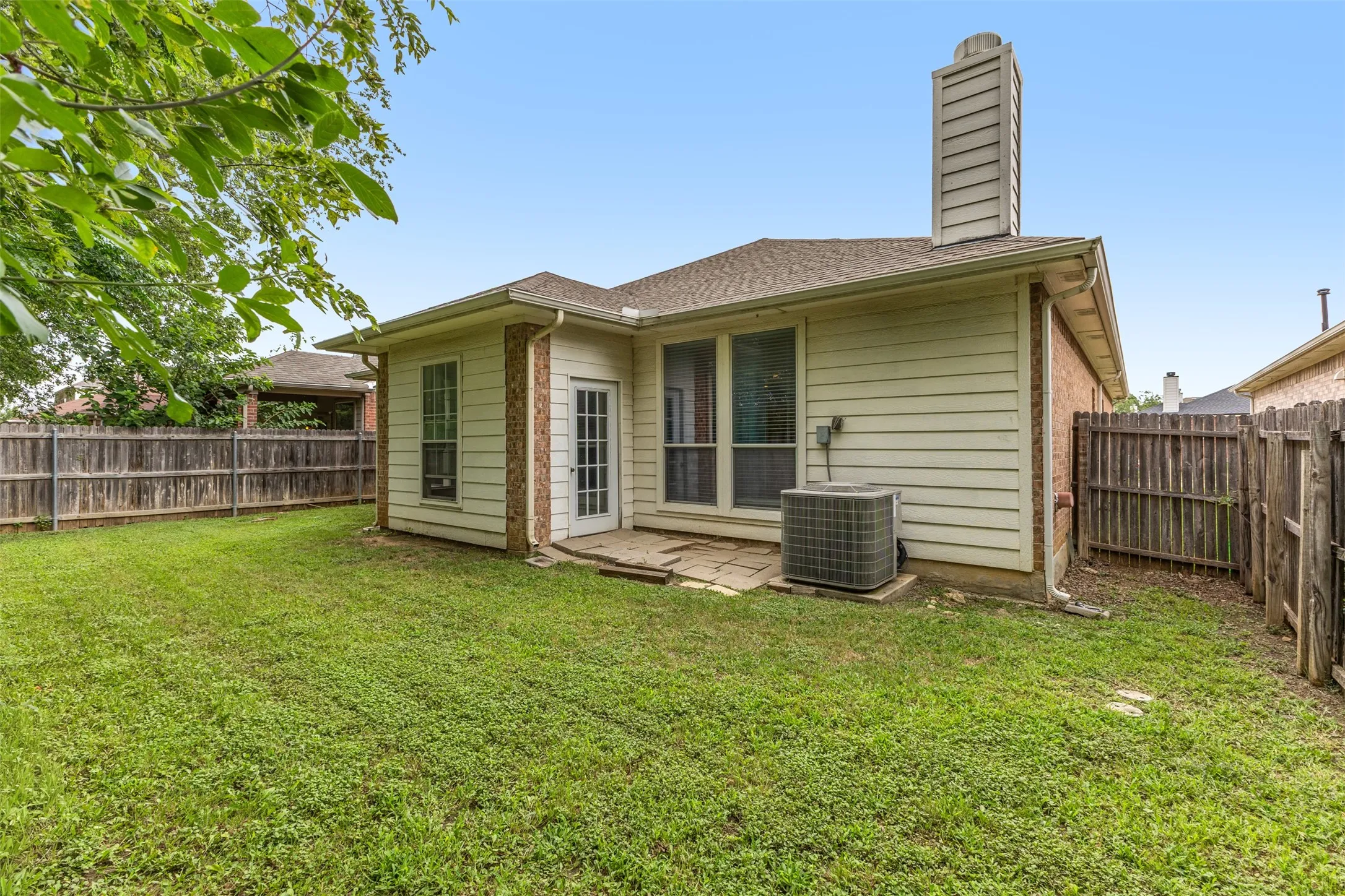Expansive grass lawn backyard featuring a wood privacy fence, a small patio, and a siding exterior