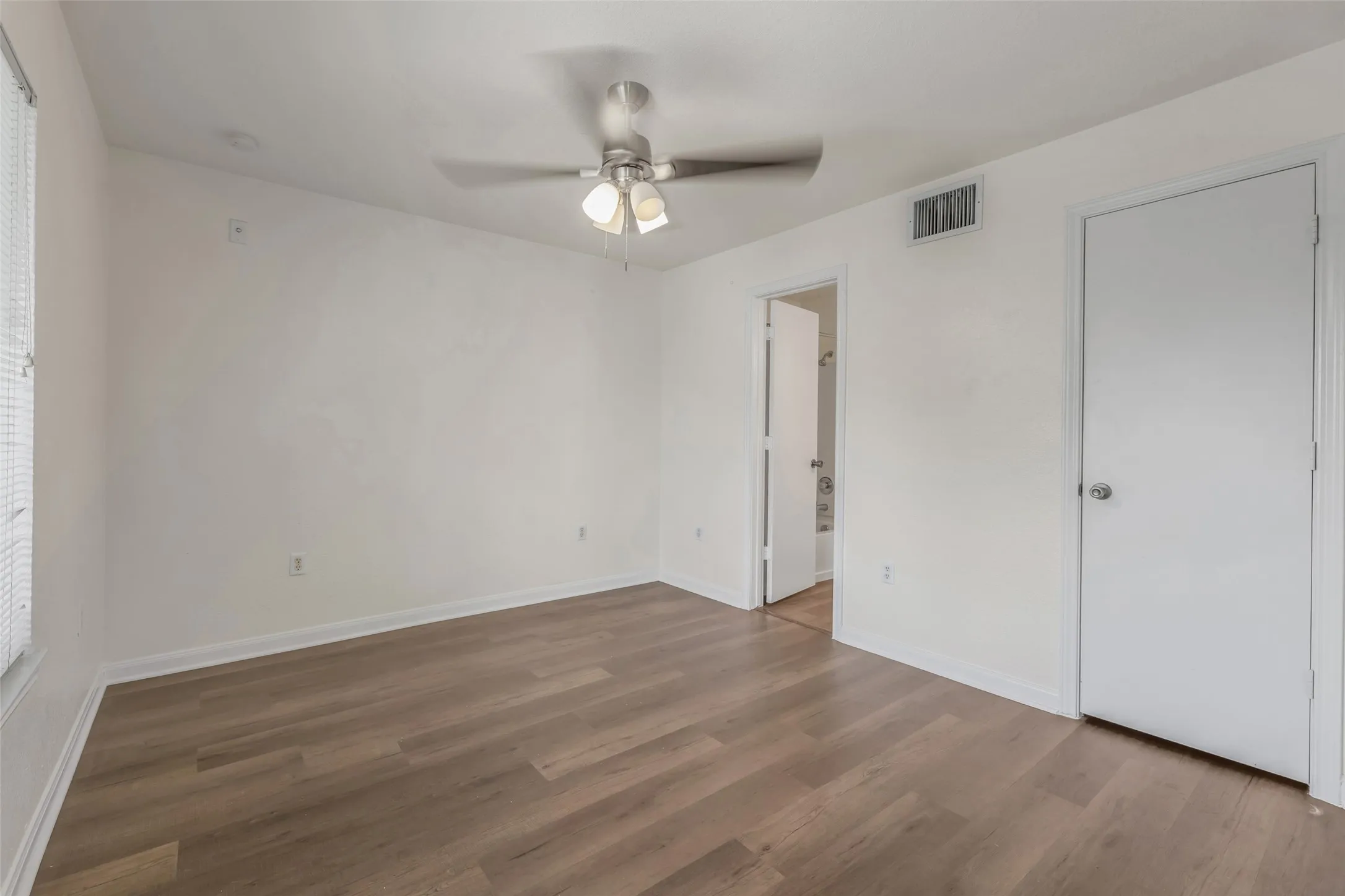 Empty bedroom with luxury vinyl plank flooring and ceiling fan