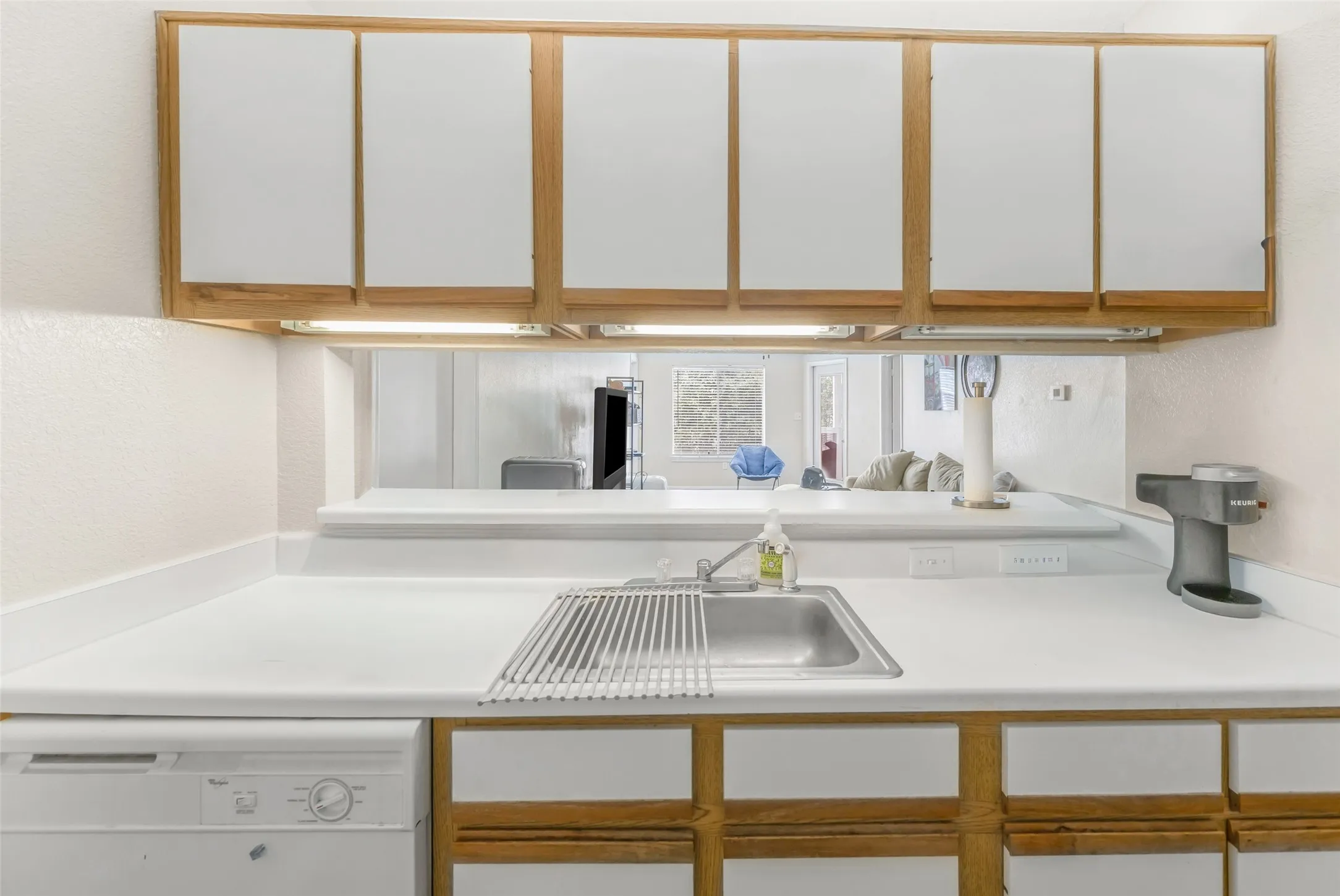 Kitchen workstation with a stainless steel sink, white countertops, and a white dishwasher