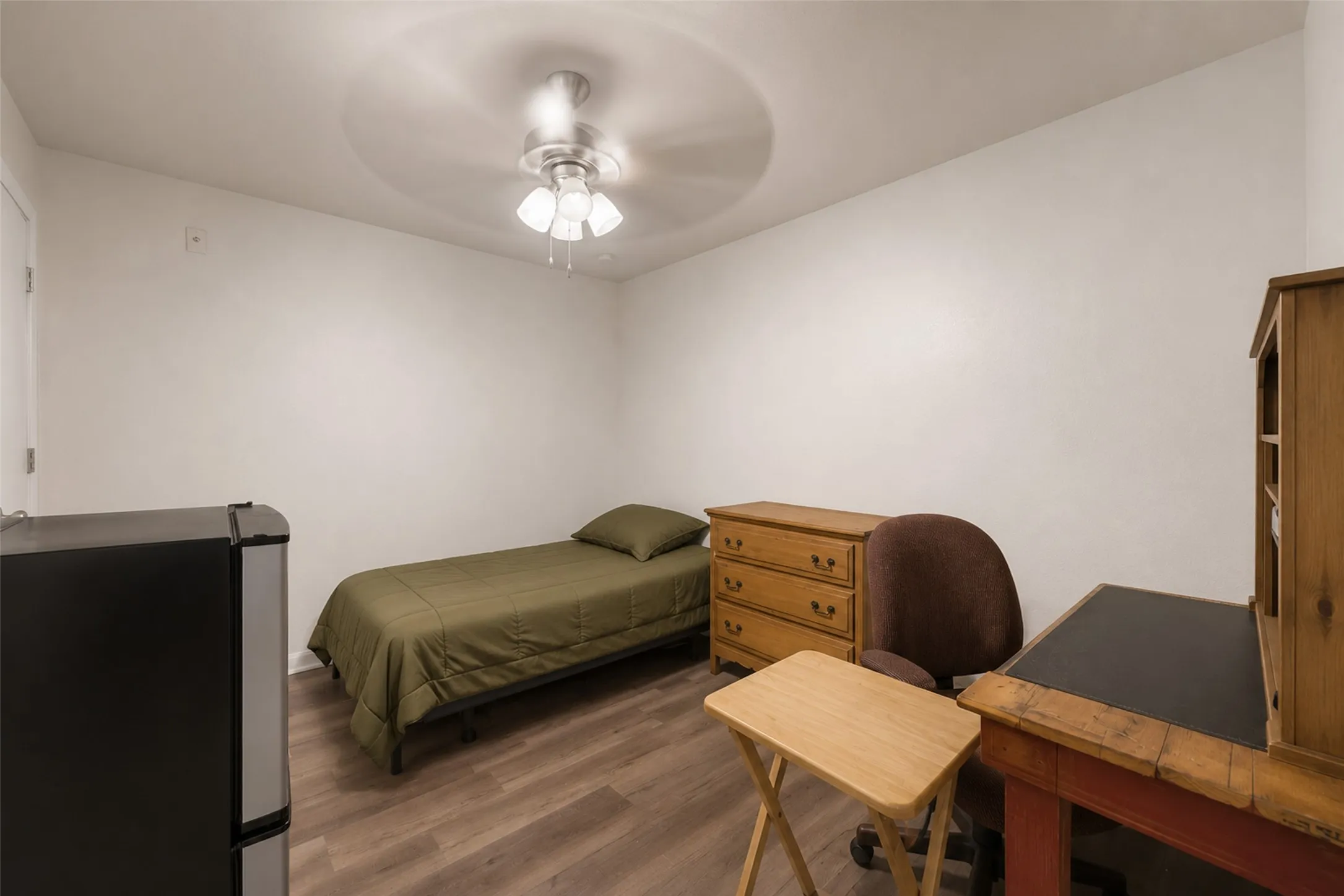 Bedroom featuring luxury vinyl plank flooring, white painted walls, and a ceiling fan with integrated lighting