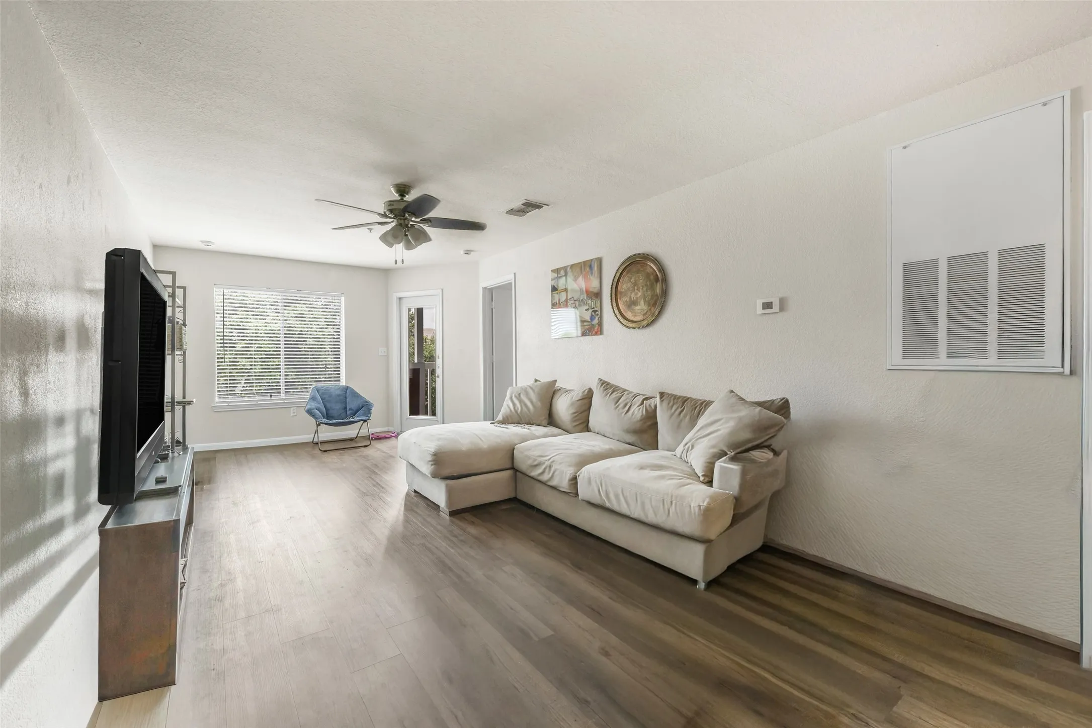 Living area featuring luxury vinyl plank wood-finish flooring, a ceiling fan, and white walls