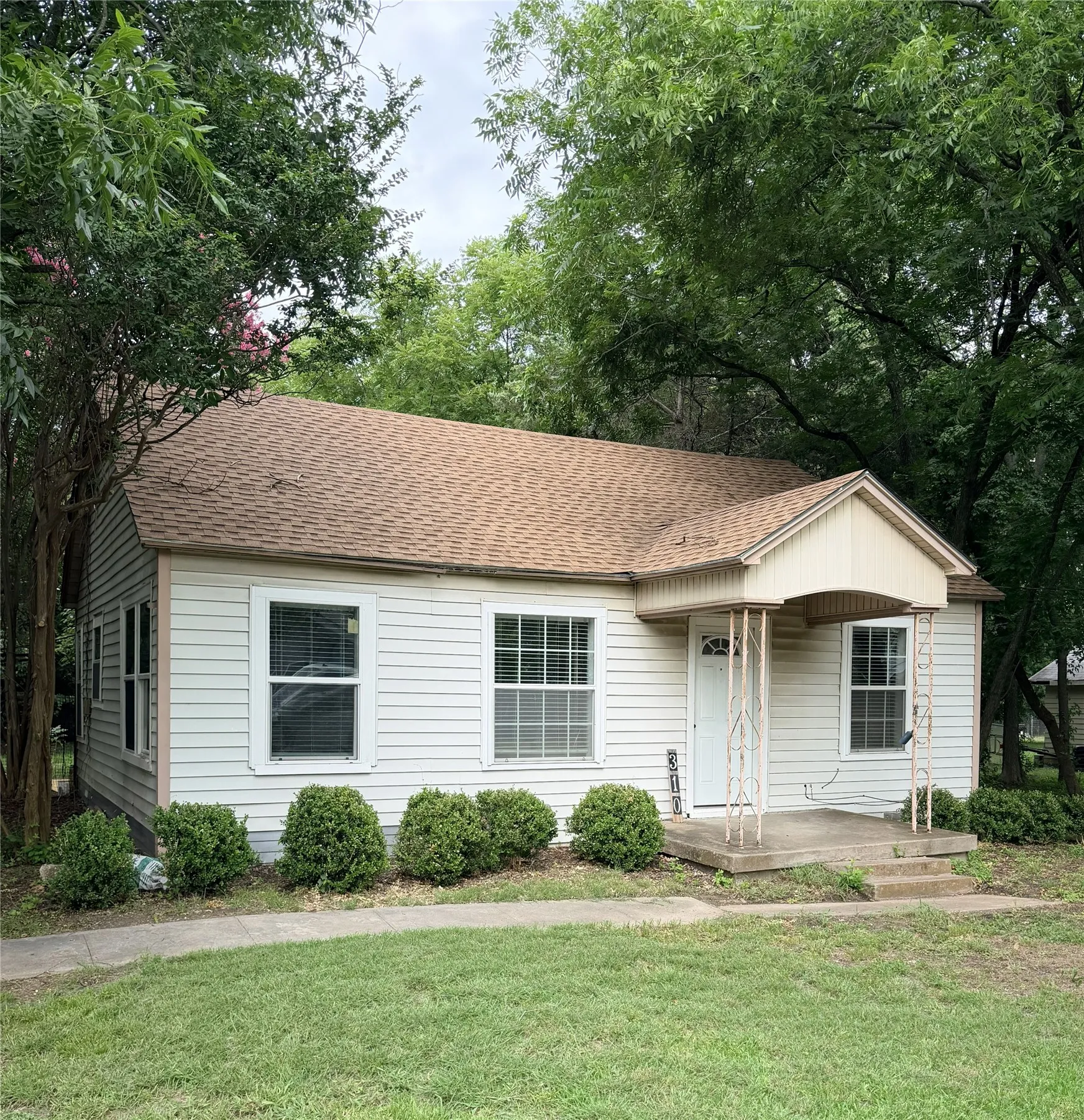 Single-story residence featuring light-colored siding and a brown shingle roof