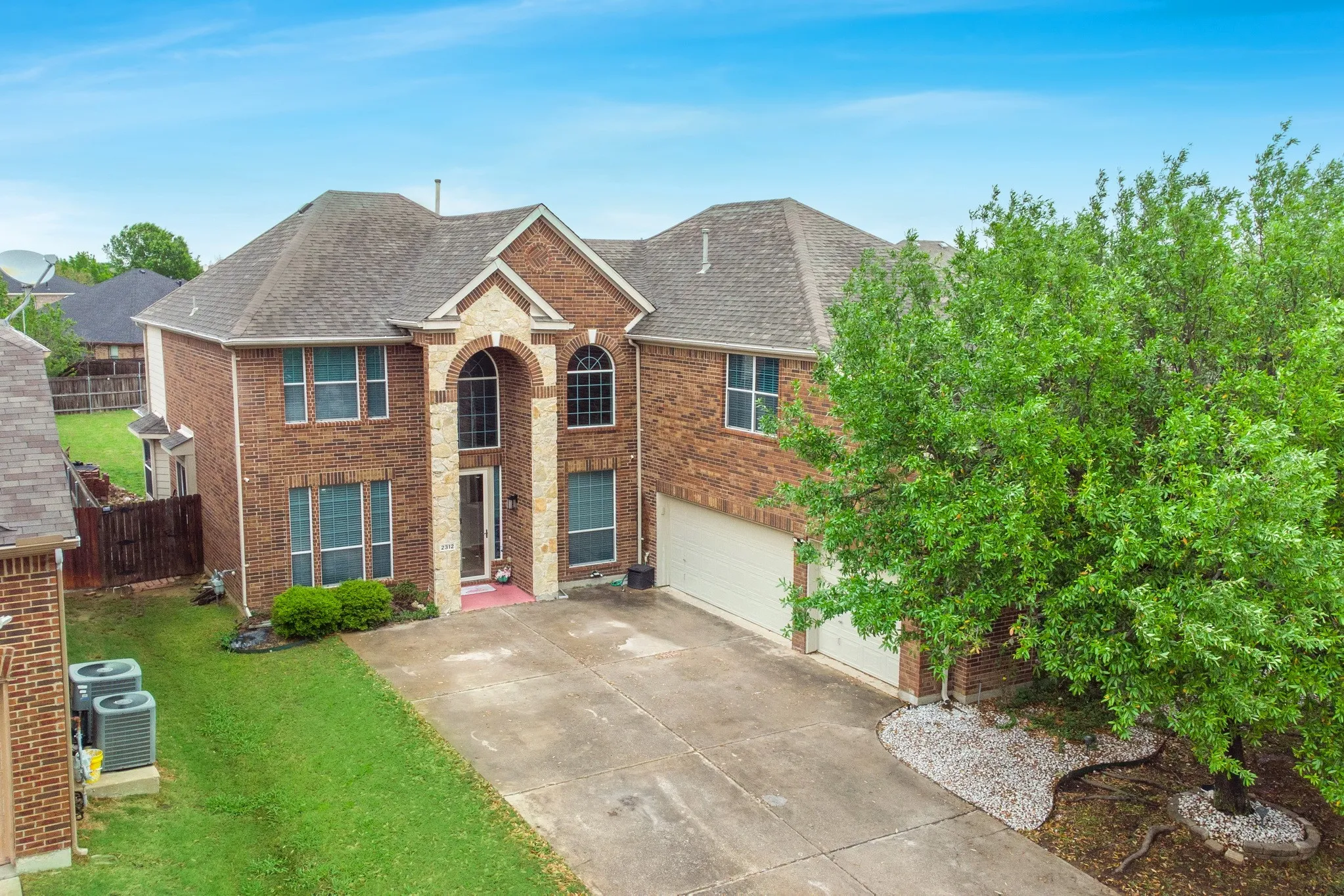 Two-story brick residence featuring a prominent arched entryway with stone accents