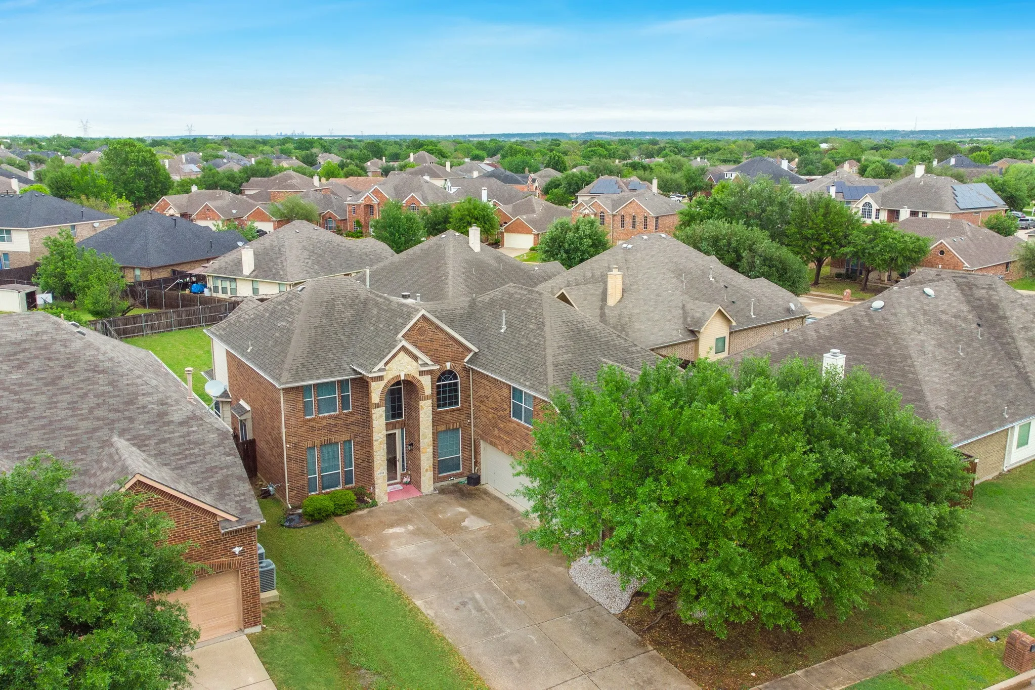 Traditional two-story brick residence with multiple gables, an arched entry, and a paved driveway
