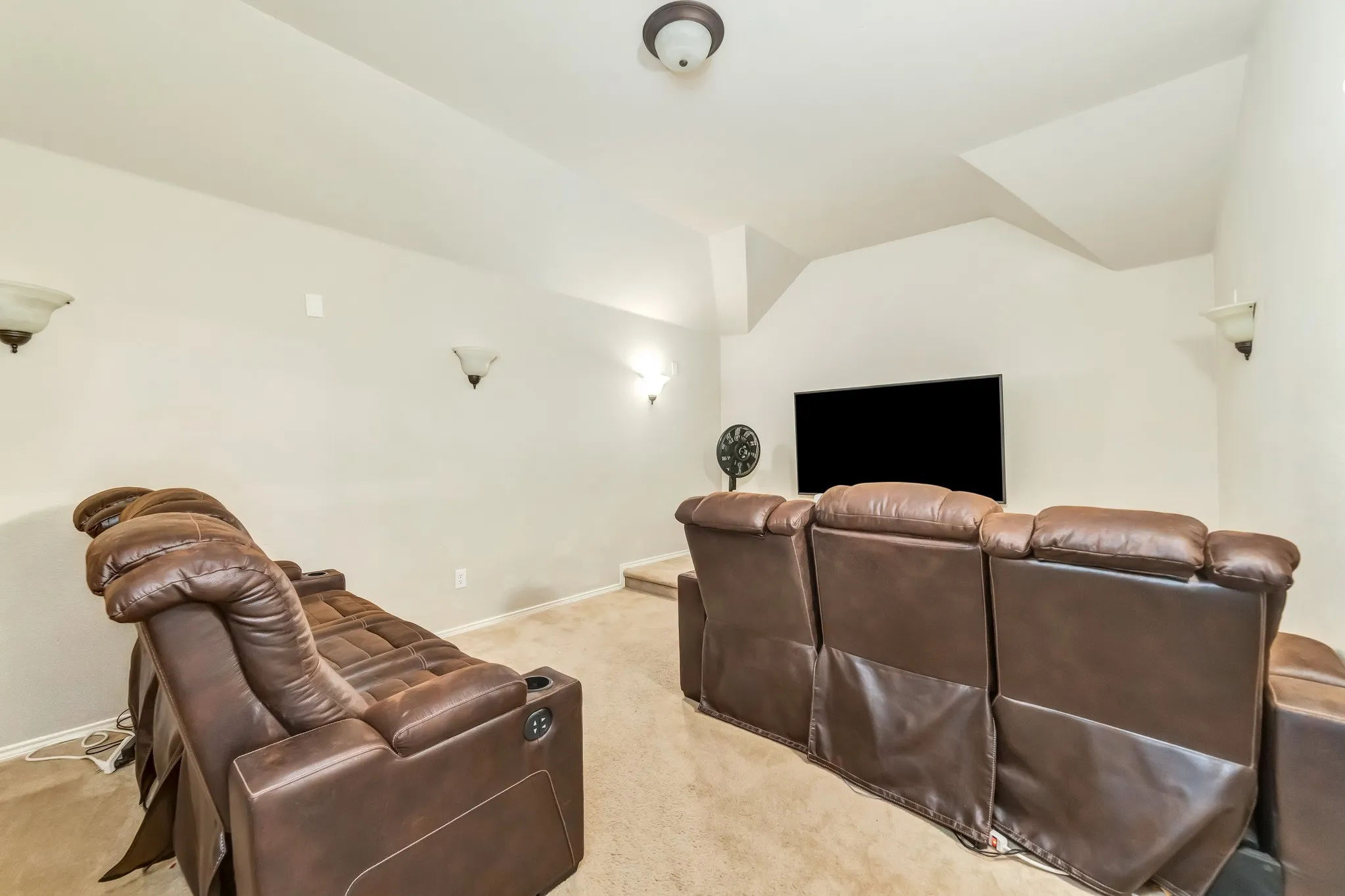 Carpeted room with a stepped platform and a wall-mounted television