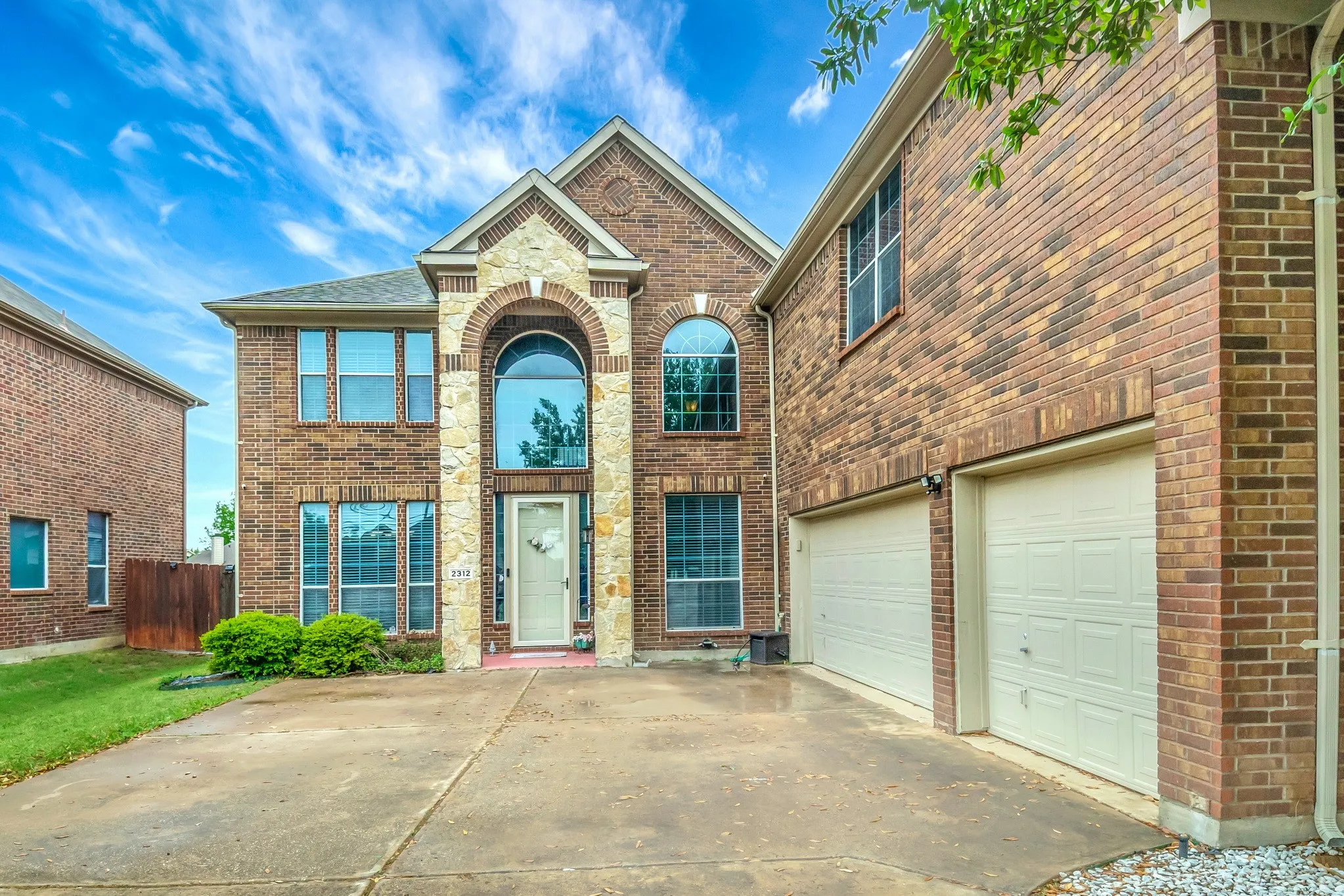 Two-story brick facade residence featuring stone accents and arched windows