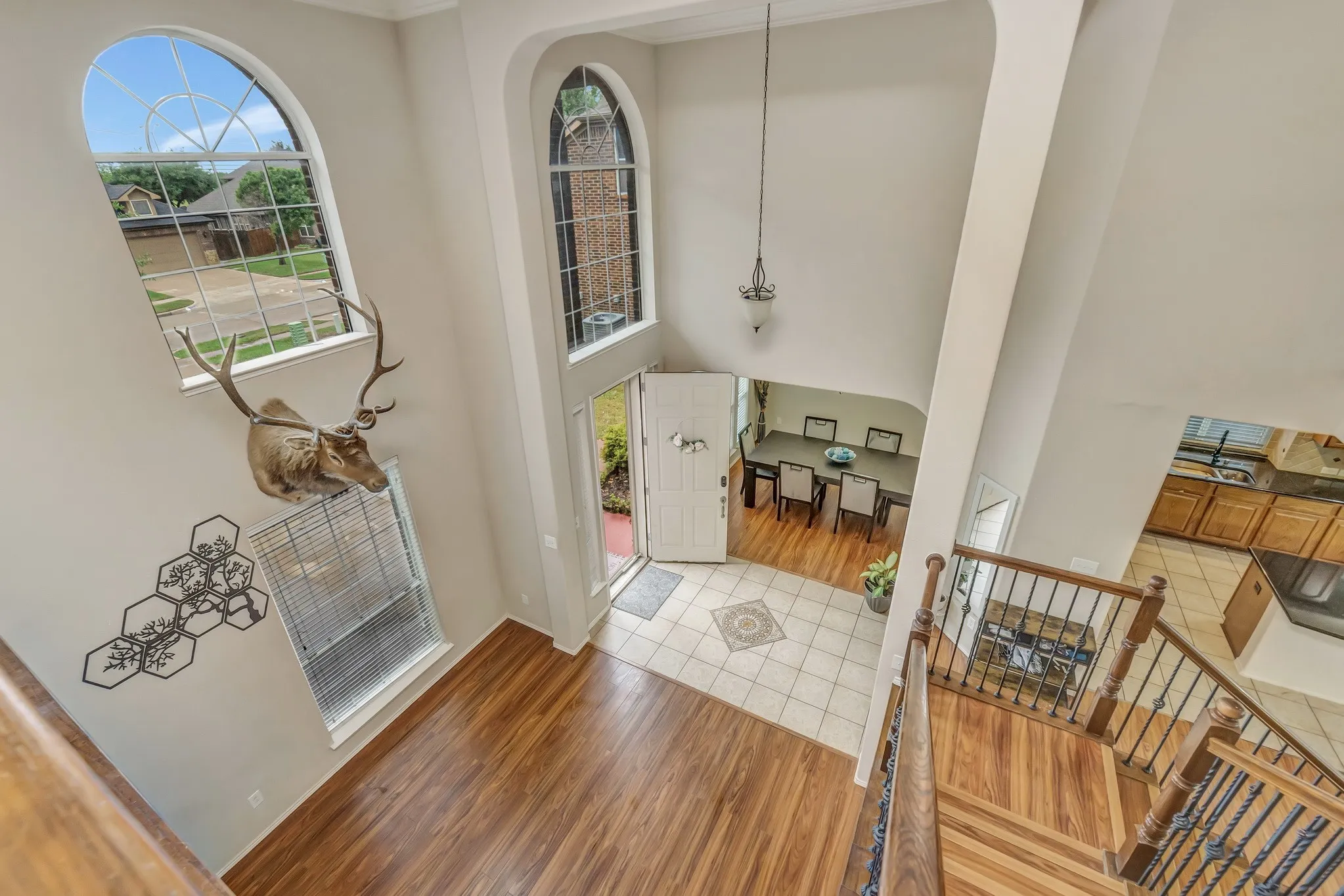 Grand foyer with soaring ceilings, wood-finish flooring, and a detailed staircase featuring wood treads and wrought iron balusters