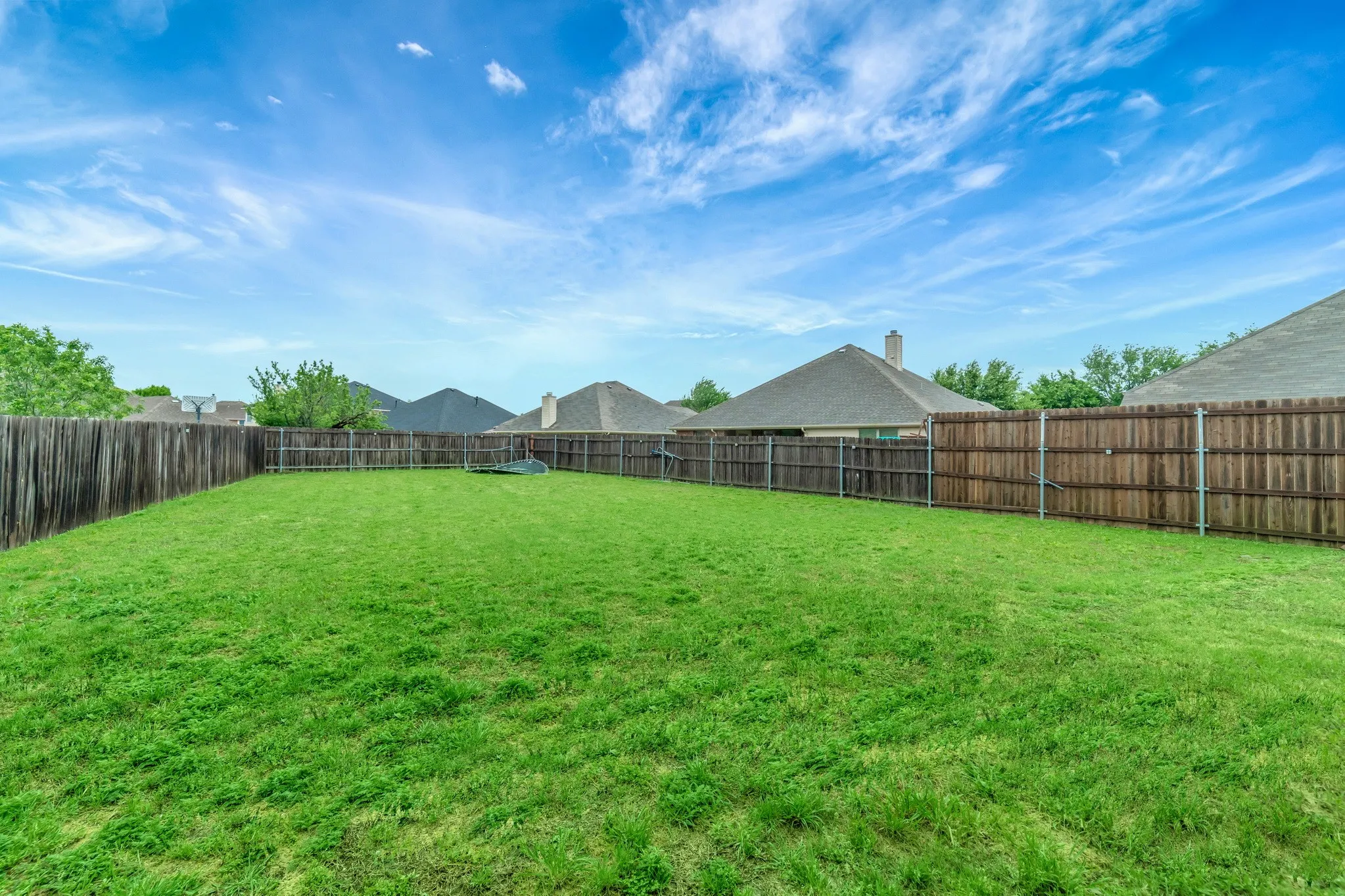 Expansive backyard featuring a lush green lawn, full wood privacy fencing, and ample open space