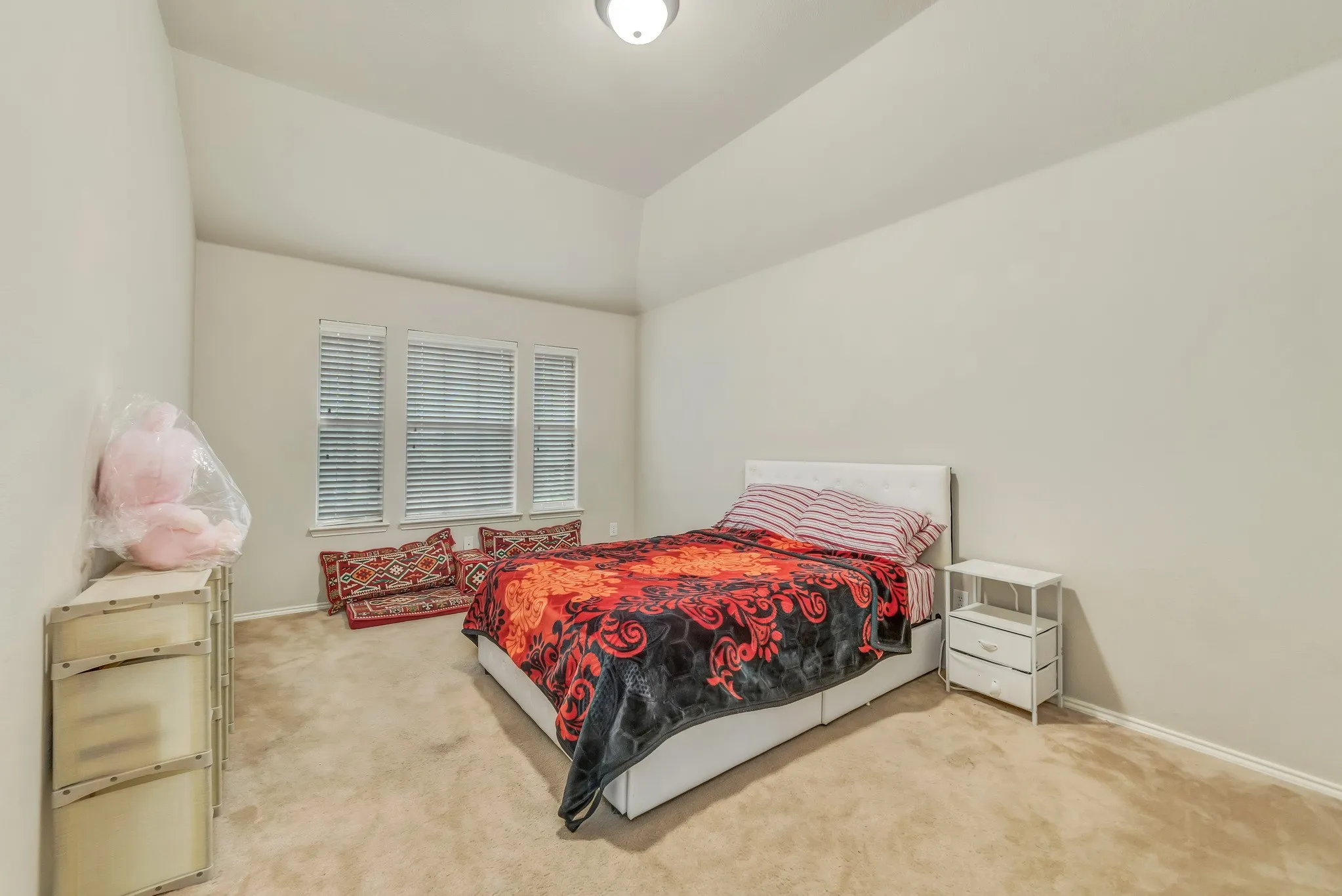 Spacious room featuring a vaulted ceiling and neutral wall tones
