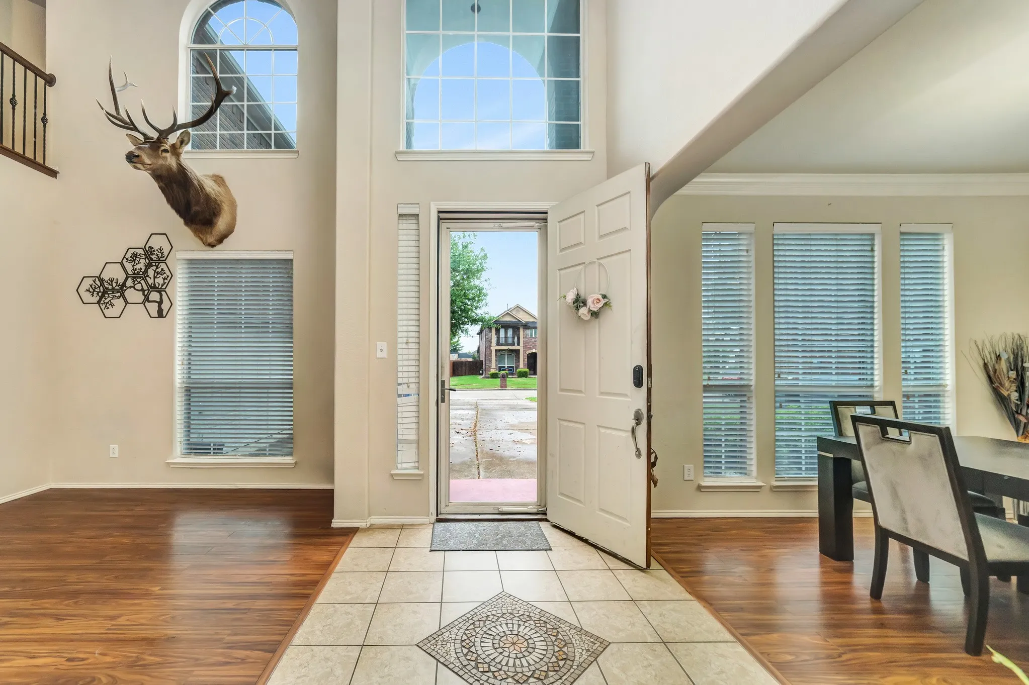 Double-height entry featuring a decorative arched window, wood-finish flooring, and a tiled entryway with an inlaid mosaic design