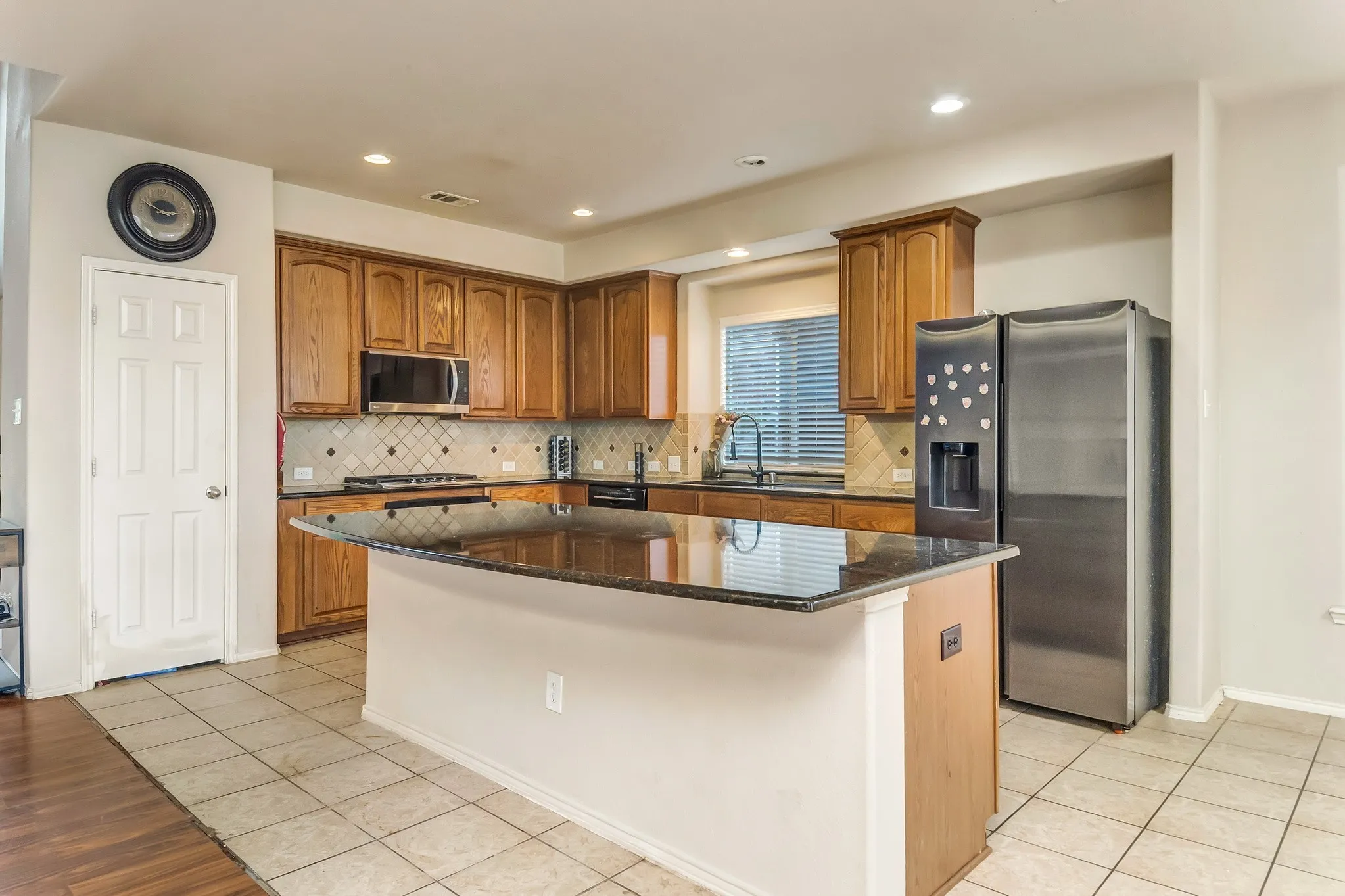 Kitchen featuring a center island with a dark granite countertop, wood cabinetry, stainless steel appliances, and tile flooring