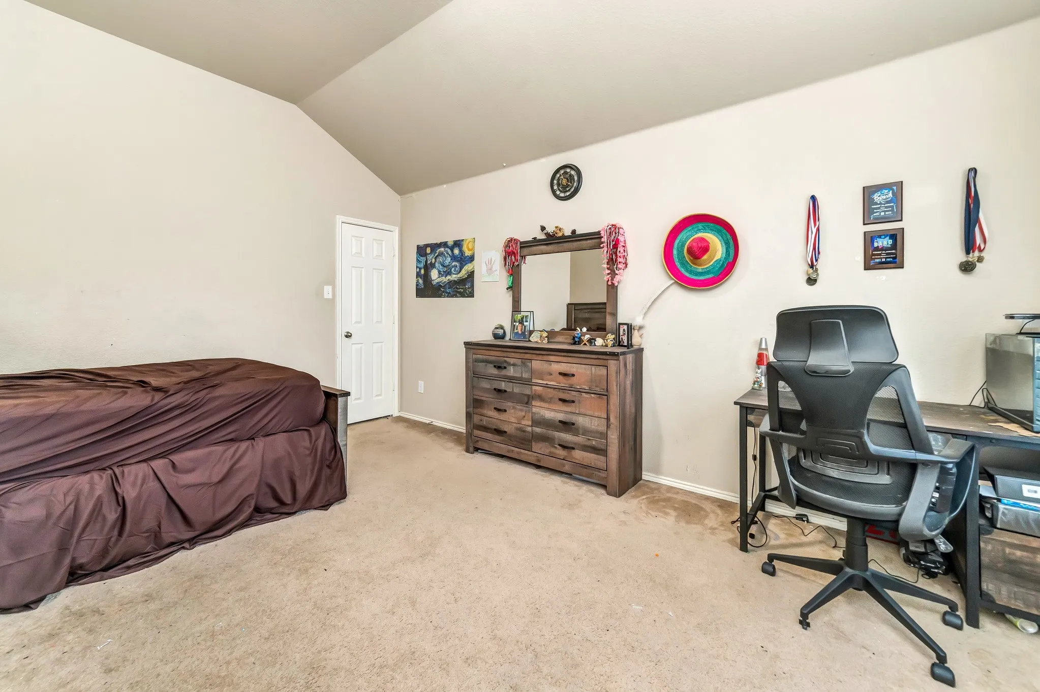 Carpeted room featuring a vaulted ceiling and light-toned walls
