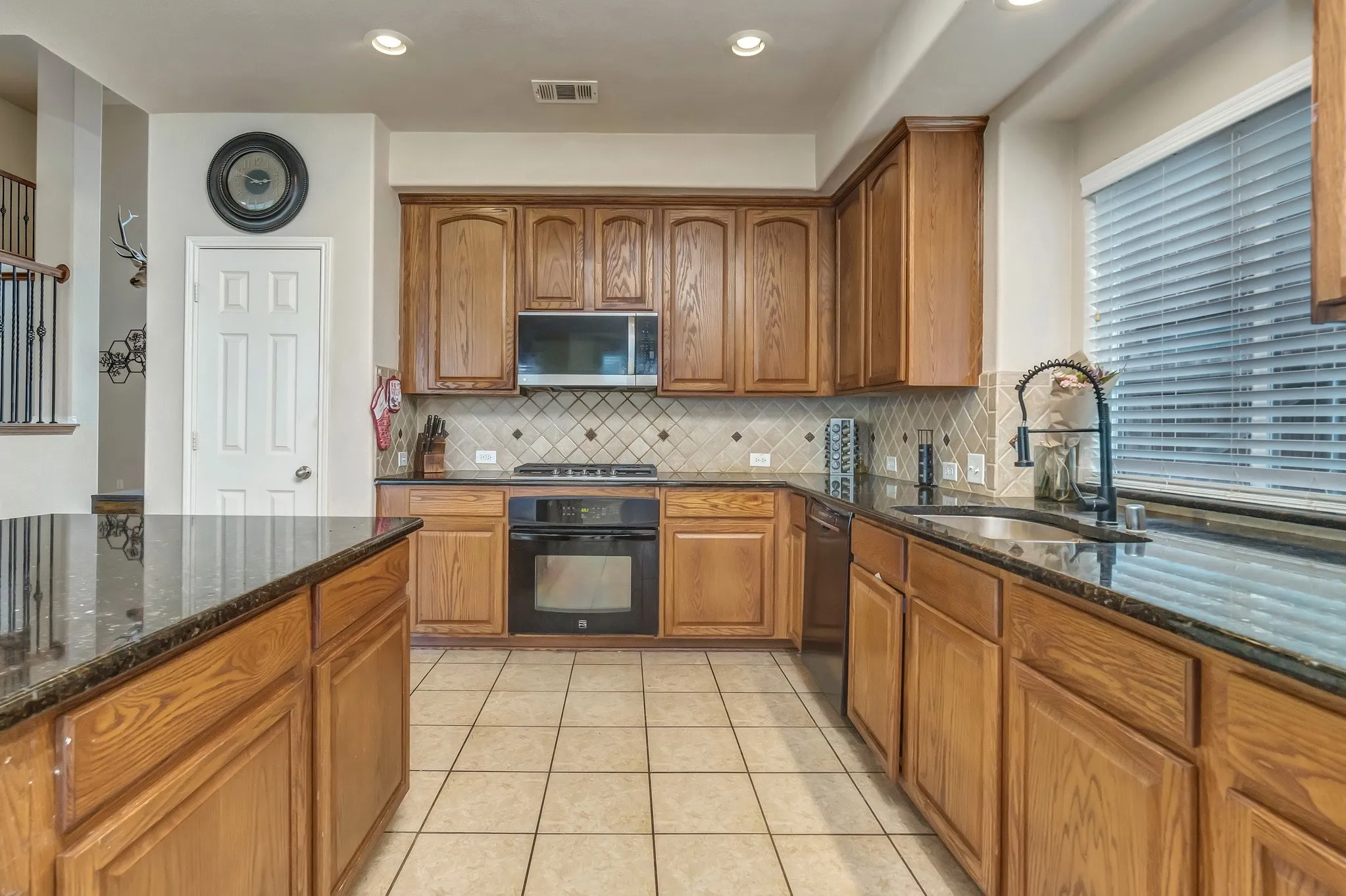 Kitchen featuring wood cabinetry, dark countertops, tiled backsplash, and recessed lighting