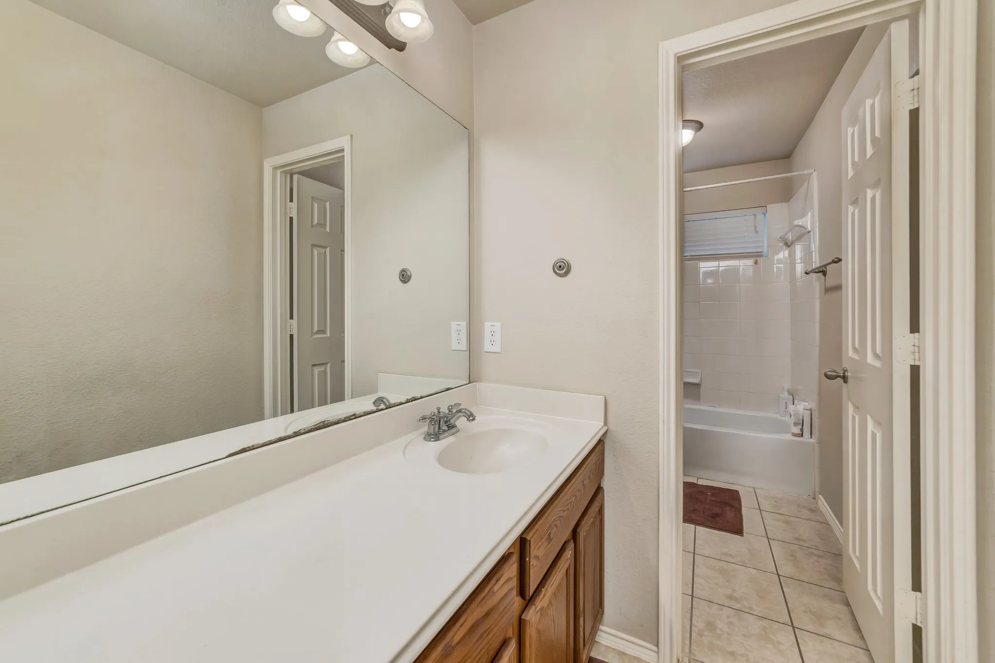 Bathroom vanity with a white countertop and integrated sink, chrome faucet, and wood-finish cabinetry