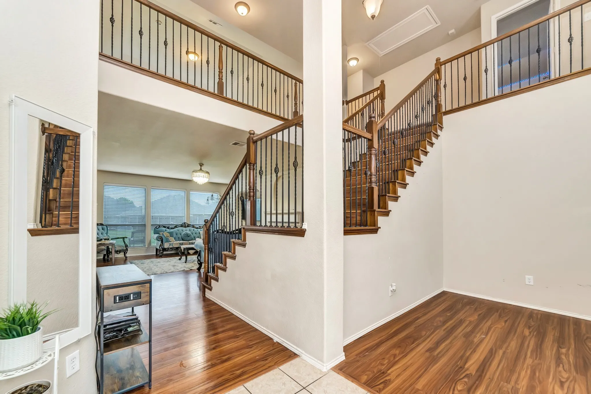 Two-story entry foyer featuring wood-finish flooring, a grand staircase with dark wood banisters and wrought iron spindles, and an open second-story landing