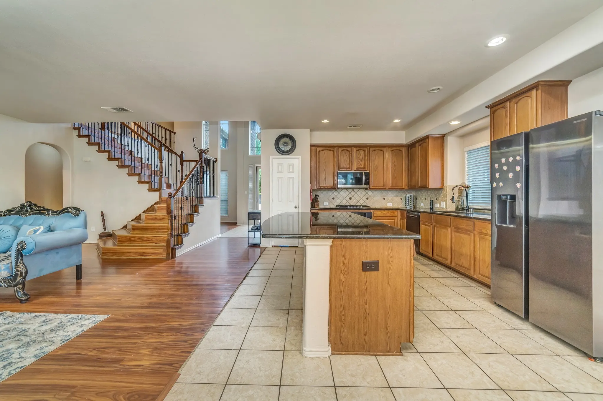 Open-concept kitchen featuring an island, wood cabinetry, stainless steel appliances, and tile flooring