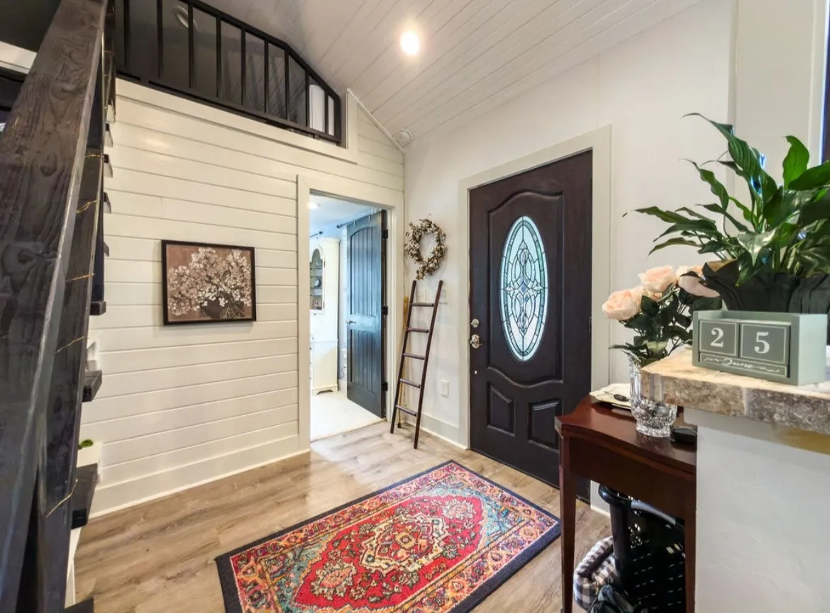 Entryway featuring a dark wood front door with an oval stained-glass insert, wood-finish flooring, white shiplap walls, and a vaulted ceiling with exposed white beams