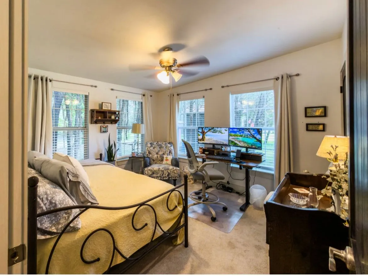Bright room featuring multiple windows with blinds, a ceiling fan, and carpeted flooring