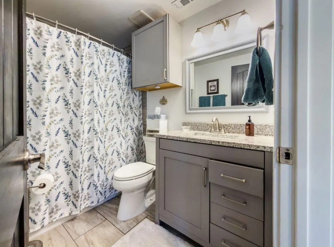 Bathroom featuring a vanity with a granite-style countertop, undermount sink, and brushed nickel faucet