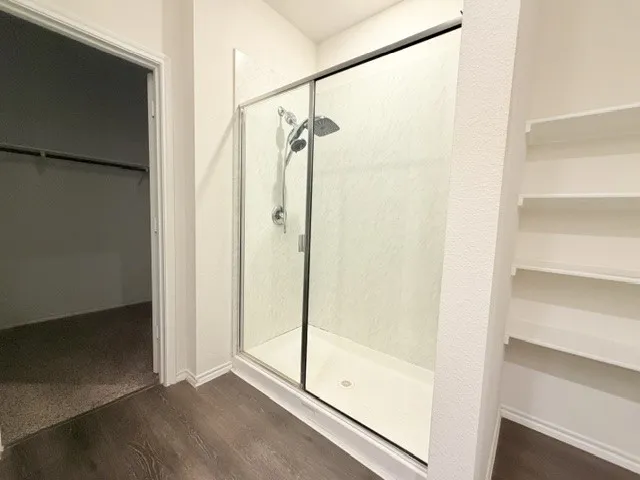 Walk-in shower with sliding glass doors, chrome fixtures, and a handheld showerhead