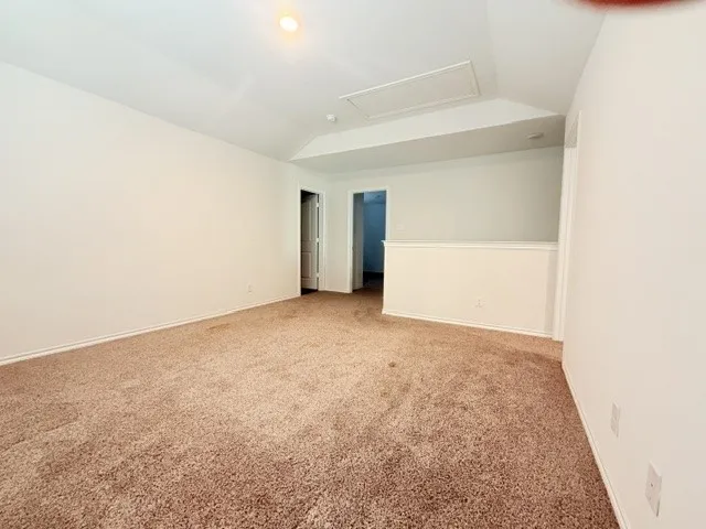 Carpeted room featuring white painted walls and a sloped ceiling with an attic access panel