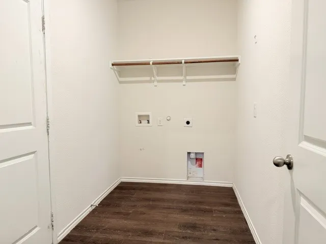 Dedicated utility space featuring wood-finish flooring, white walls, and a built-in shelf with hanging rod