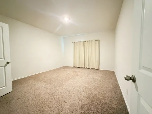 Neutral-toned carpeting spans the floor, complemented by white walls and a recessed ceiling light