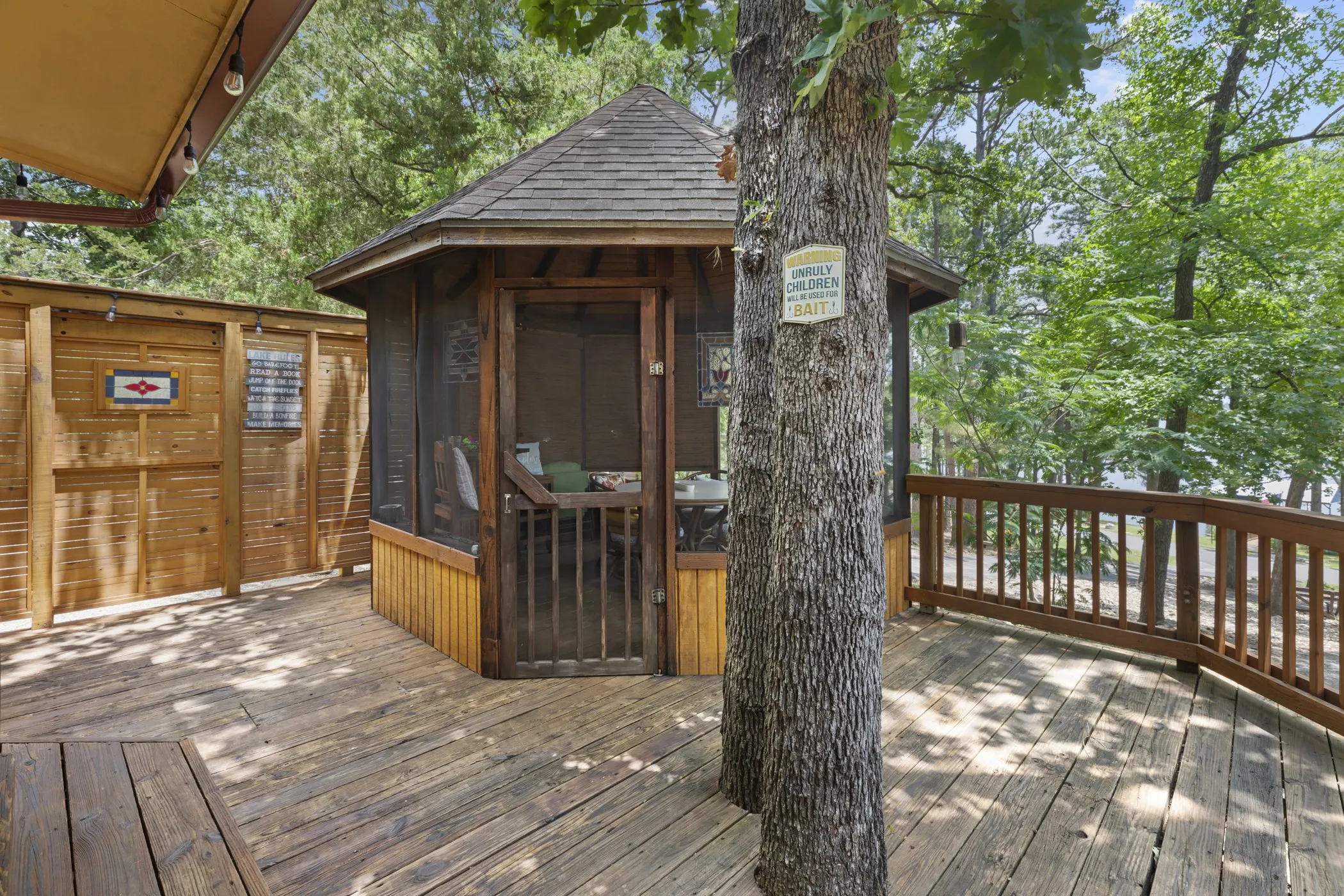 Screened gazebo with a shingled roof, set on a multi-level wood deck