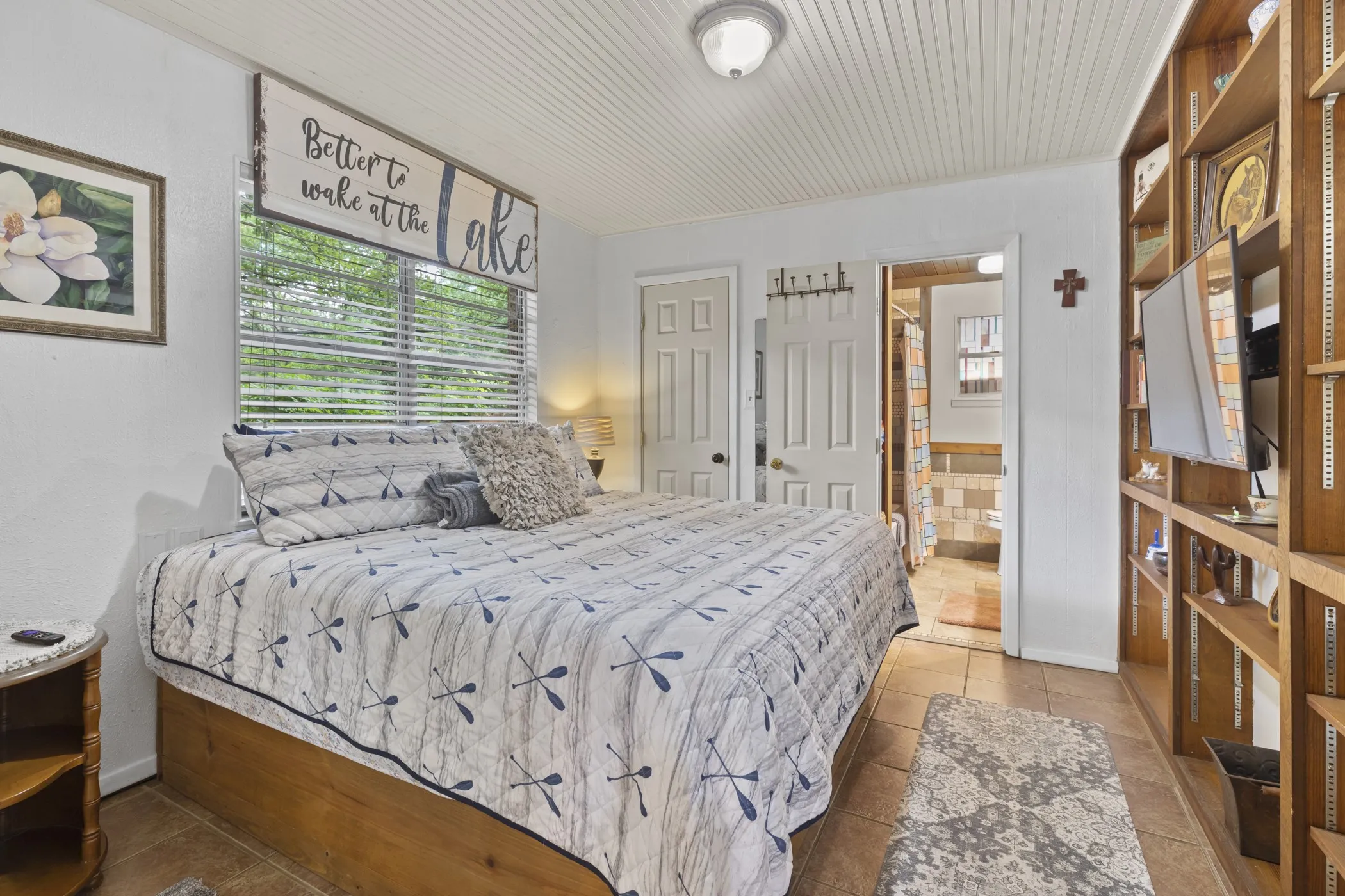 Bedroom featuring a white beadboard ceiling, a window with blinds, and built-in shelving