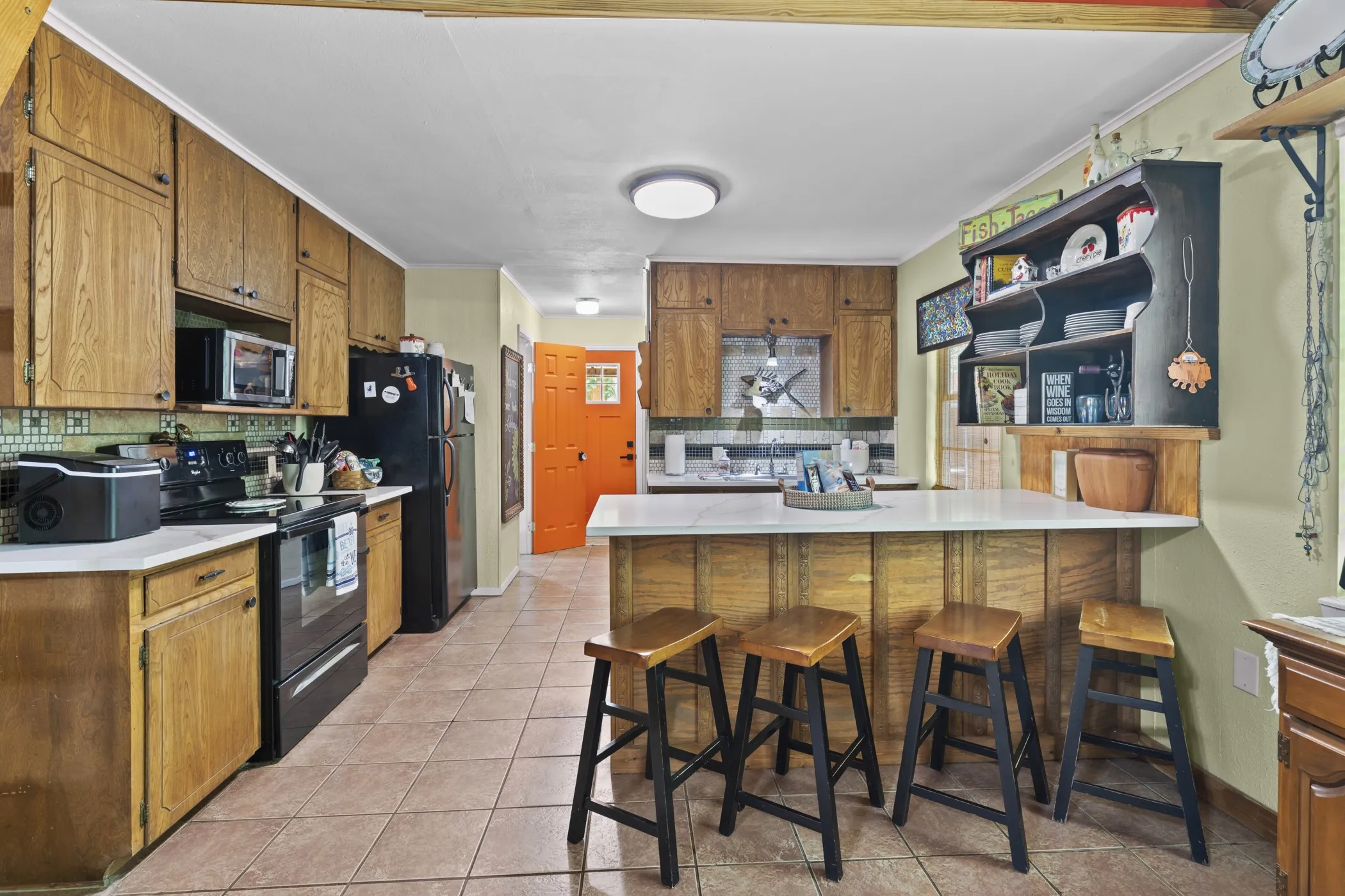 Kitchen featuring wood cabinetry, tile flooring, solid surface countertops, and a built-in breakfast bar with seating