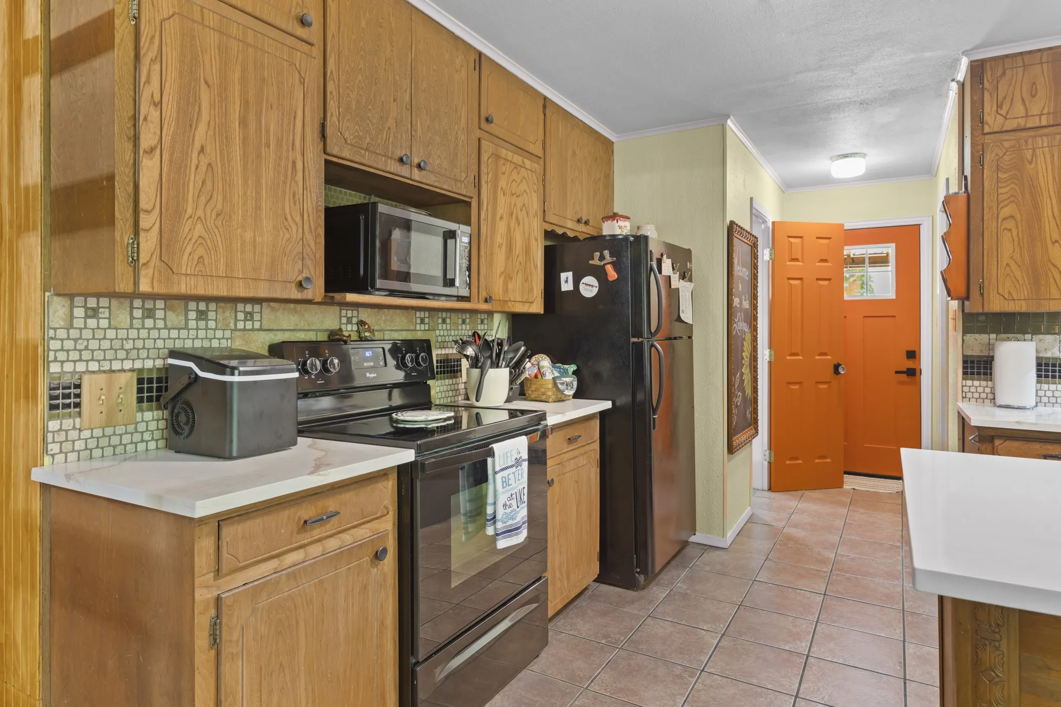 Kitchen featuring wood-finish cabinetry, light-toned countertops, and a mosaic tile backsplash