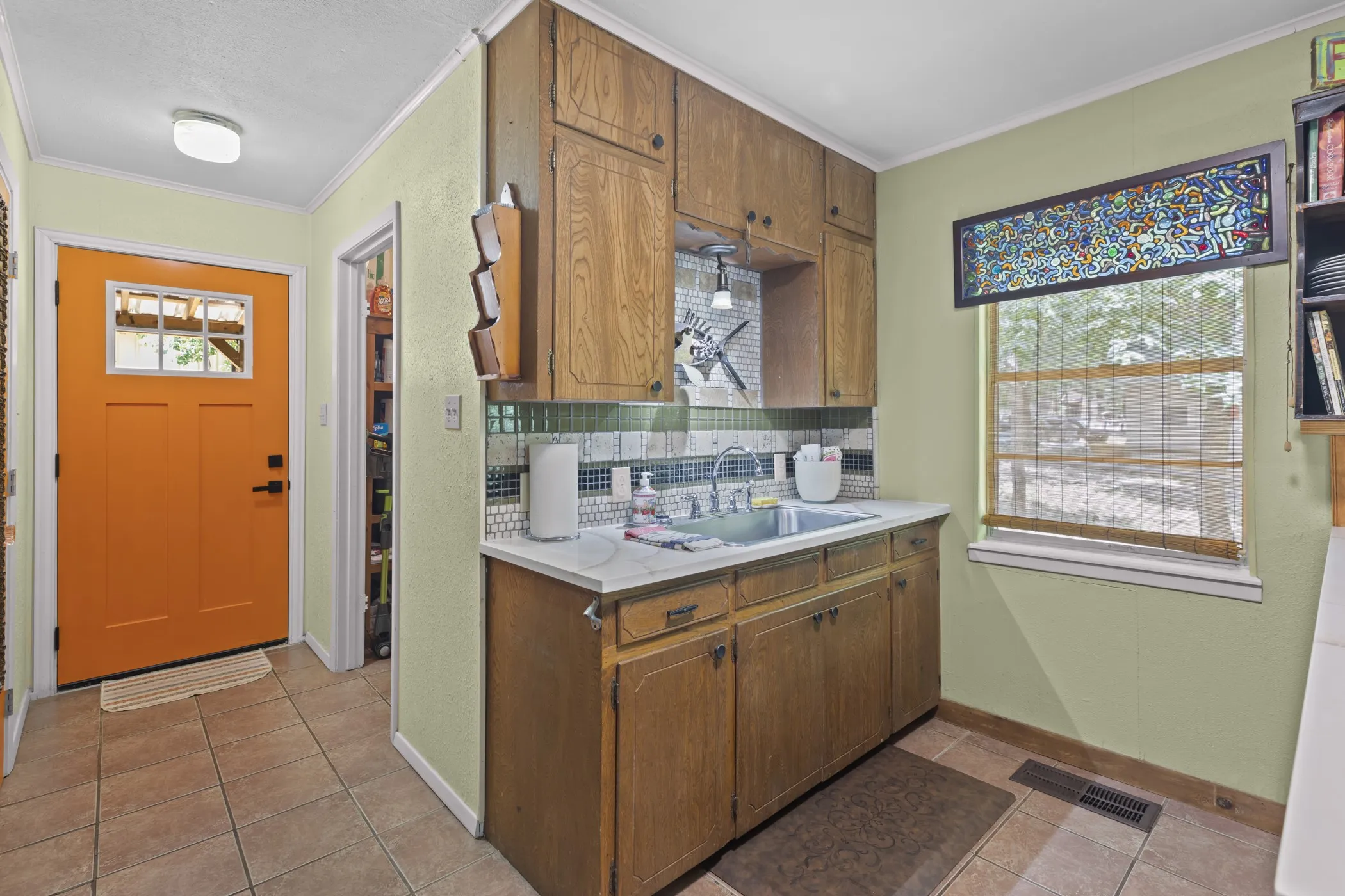 Kitchen area featuring wood cabinetry, a double basin sink, and a tiled backsplash