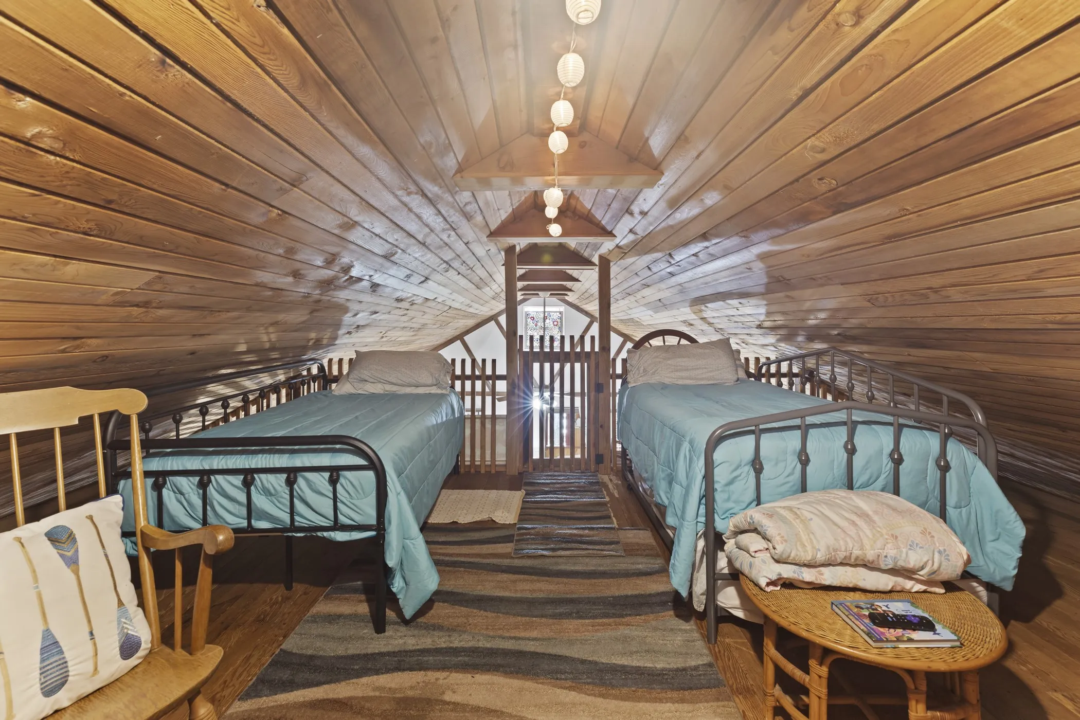 Wood-paneled room featuring sloped ceilings, two metal-frame beds, and wood-finish flooring
