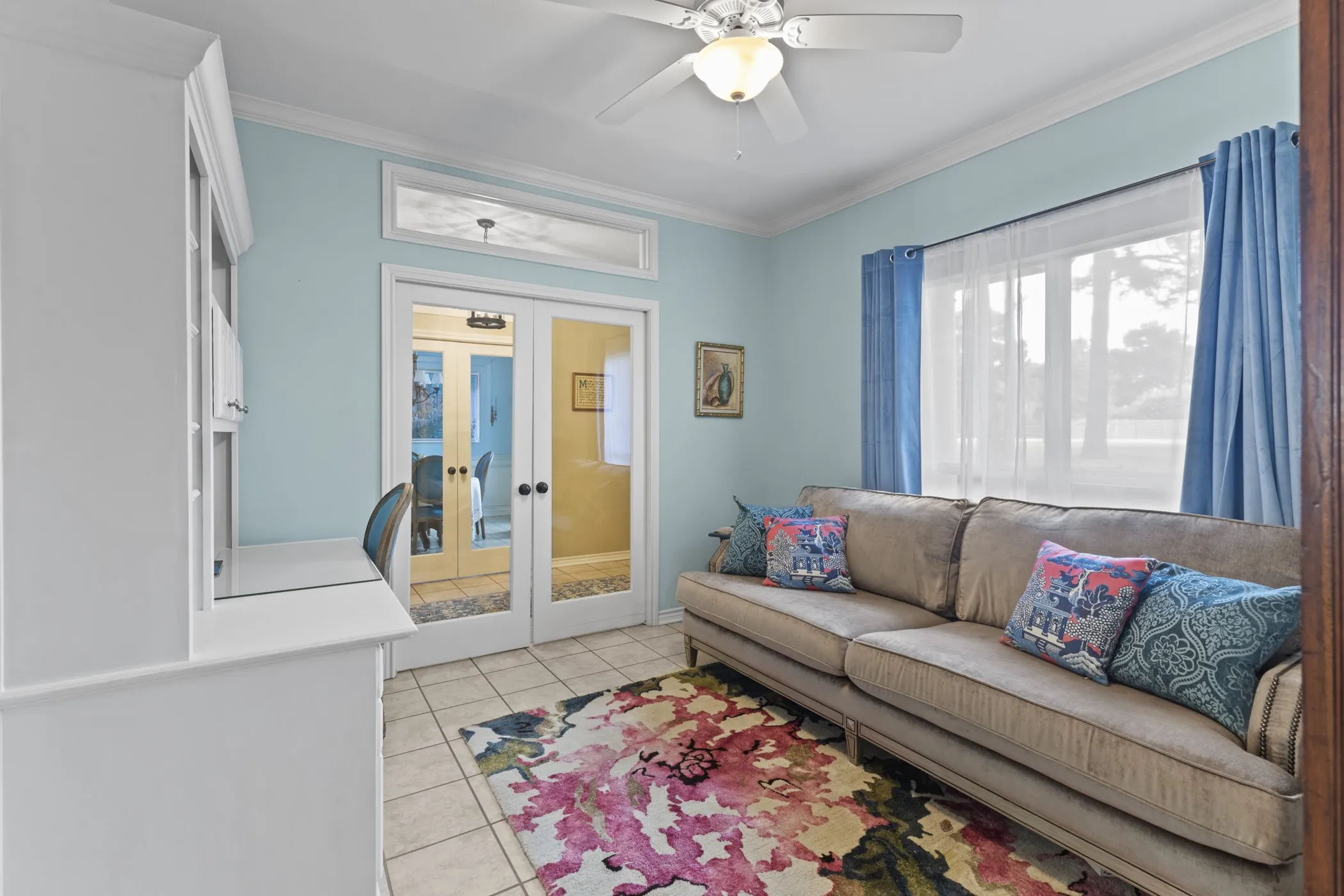 Light-filled room featuring a large window with sheers, a ceiling fan with integrated lighting, and tile flooring
