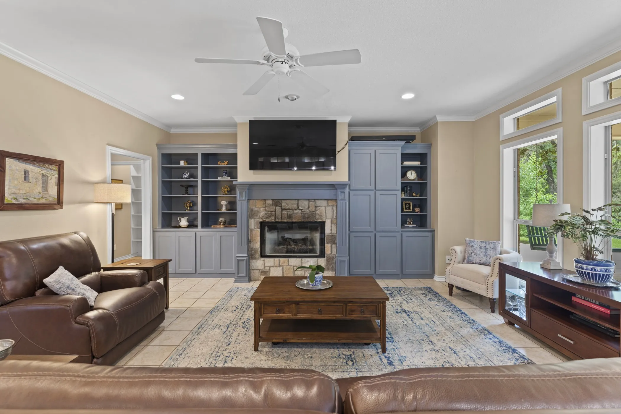 Living area featuring a stone-faced fireplace with a mantel, flanked by built-in cabinetry and shelving