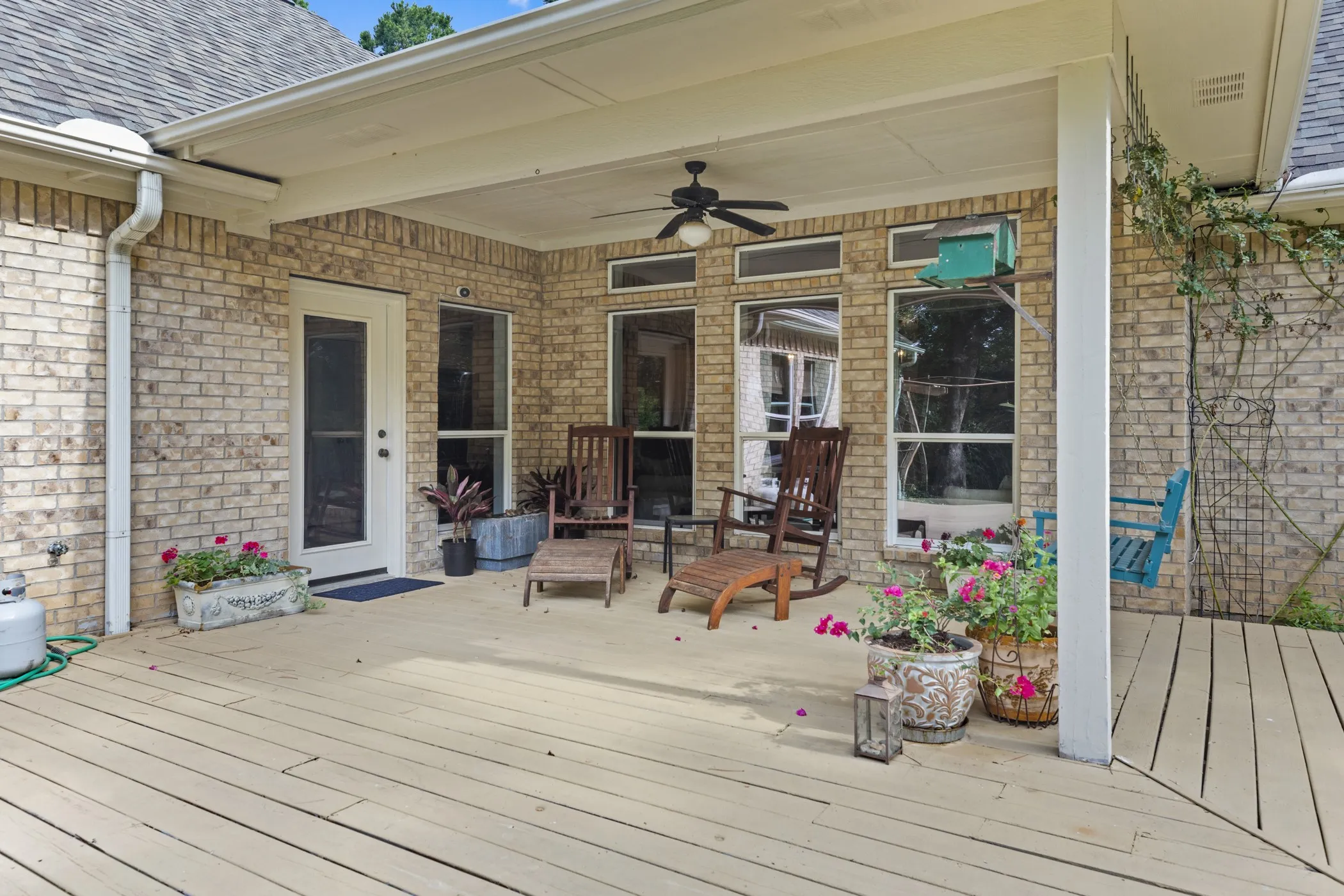 Expansive outdoor deck featuring wood-finish flooring, a covered patio area, and a ceiling fan