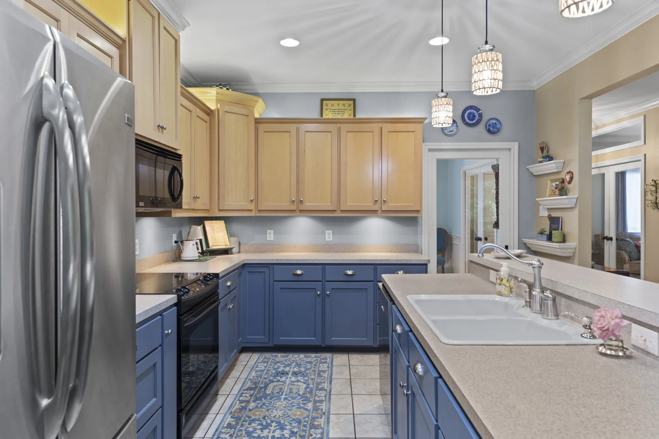 Kitchen featuring two-tone cabinetry with wood-finish upper cabinets and blue lower cabinets, stainless steel appliances, a double basin sink, and recessed lighting