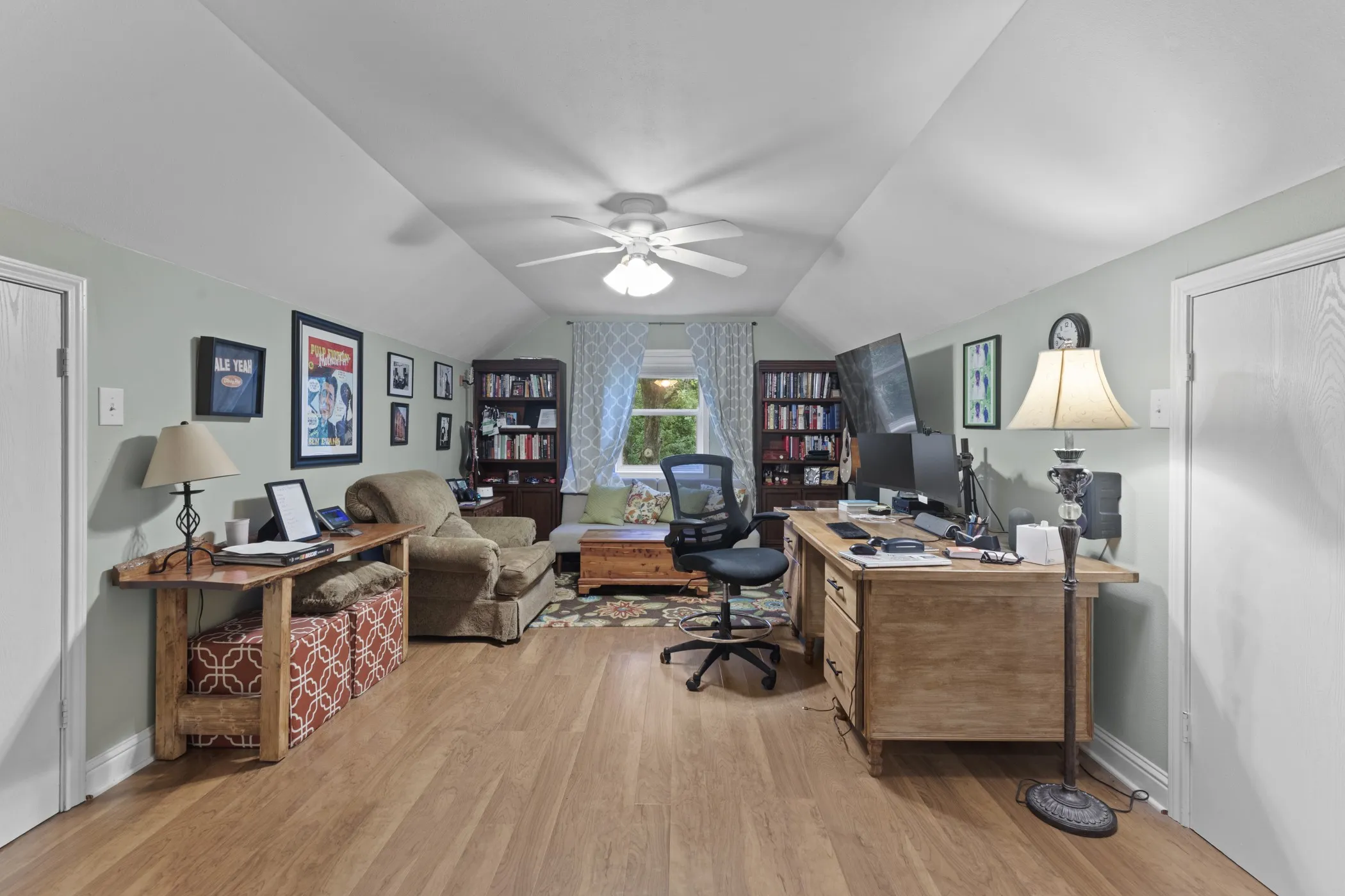 Spacious room featuring light wood-finish flooring, a ceiling fan, and sloped ceilings