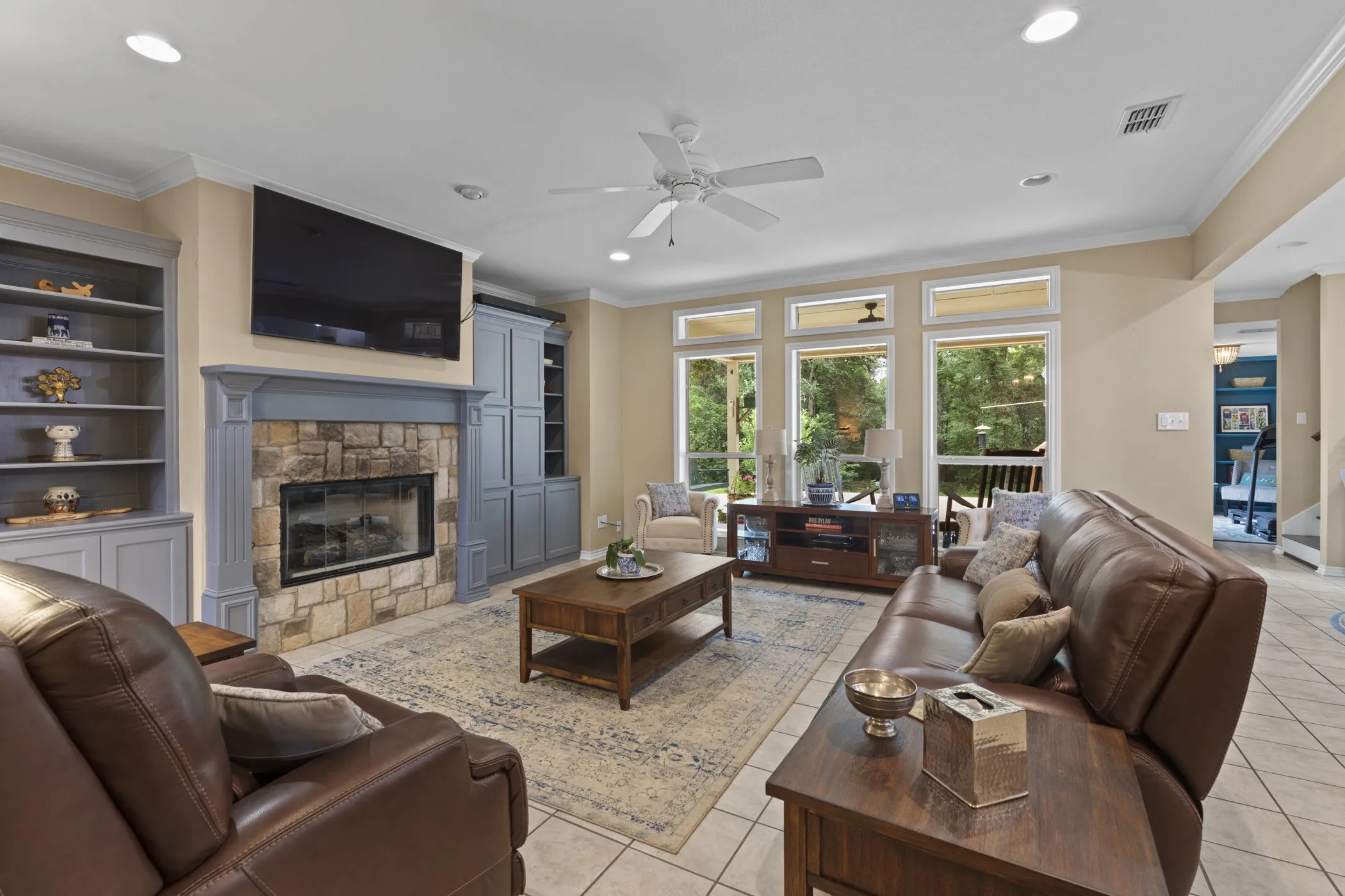 Living area featuring a stone-faced fireplace with a painted wood mantel, flanked by built-in cabinetry and shelving