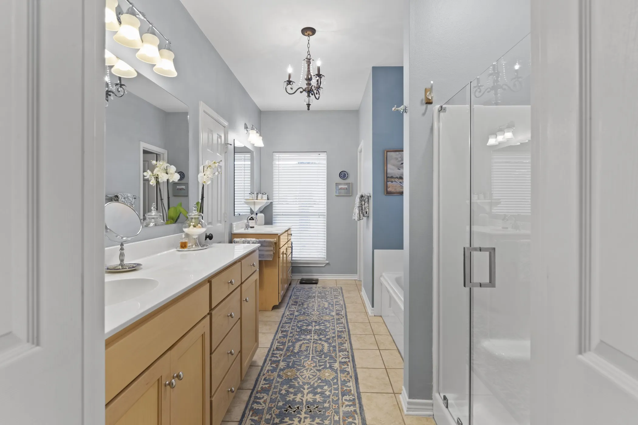 Double vanity with light wood cabinetry, white countertops, and undermount sinks