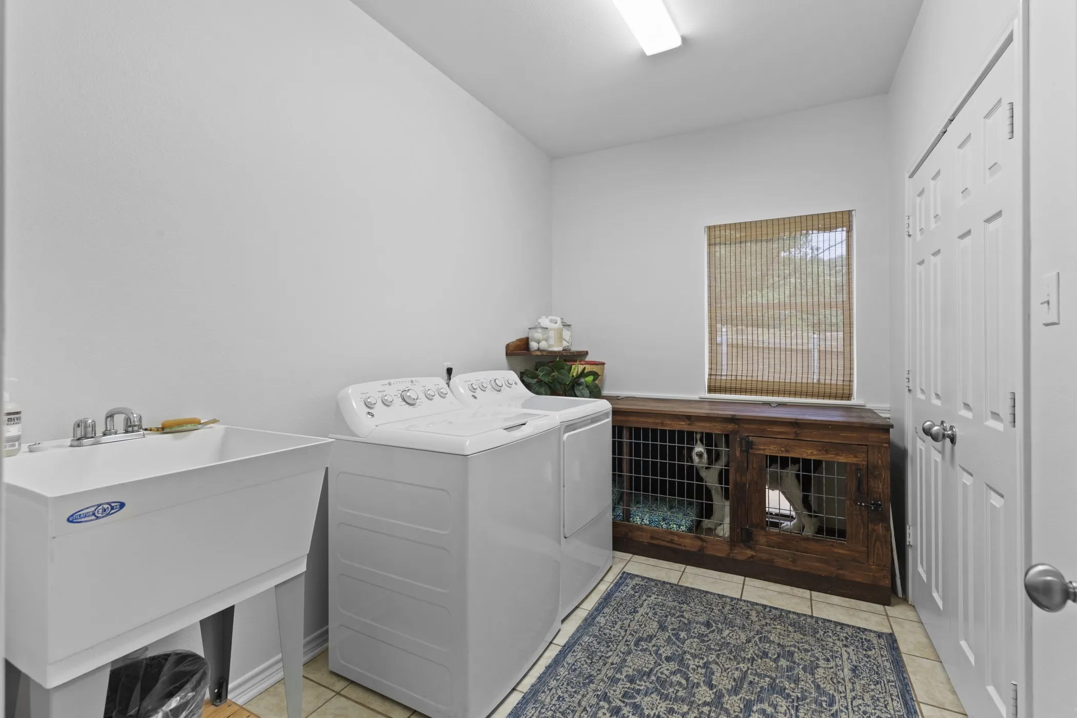 Utility room featuring a laundry sink, side-by-side washer and dryer, and ceramic tile flooring