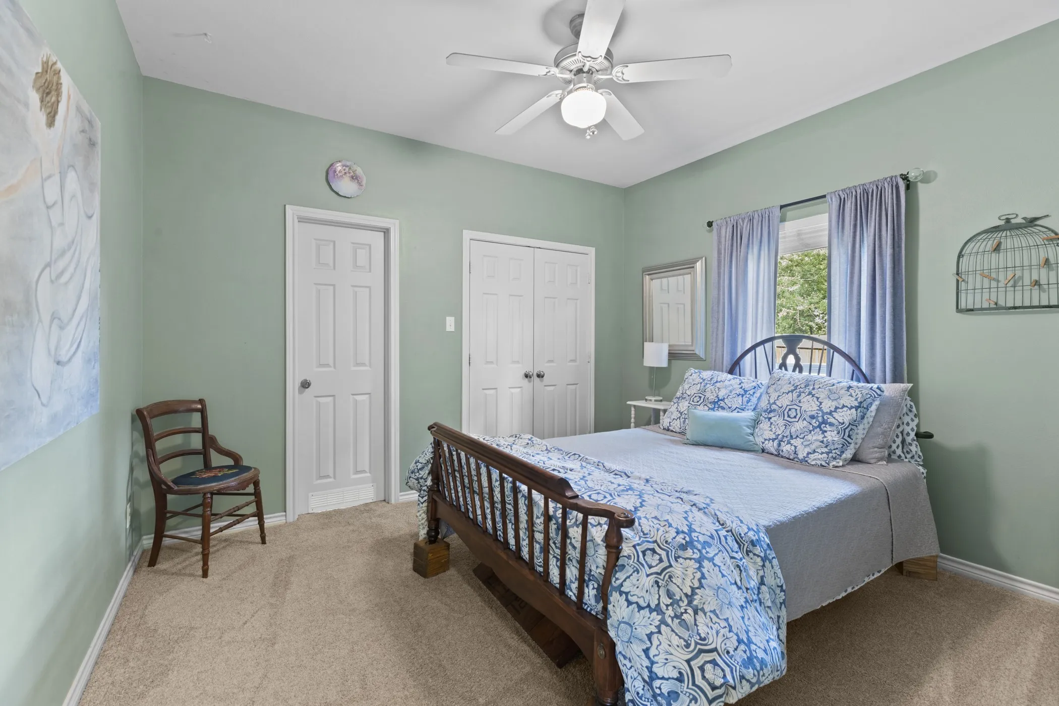 Interior room featuring neutral carpet flooring, a window with natural light, a ceiling fan, and two white panel doors