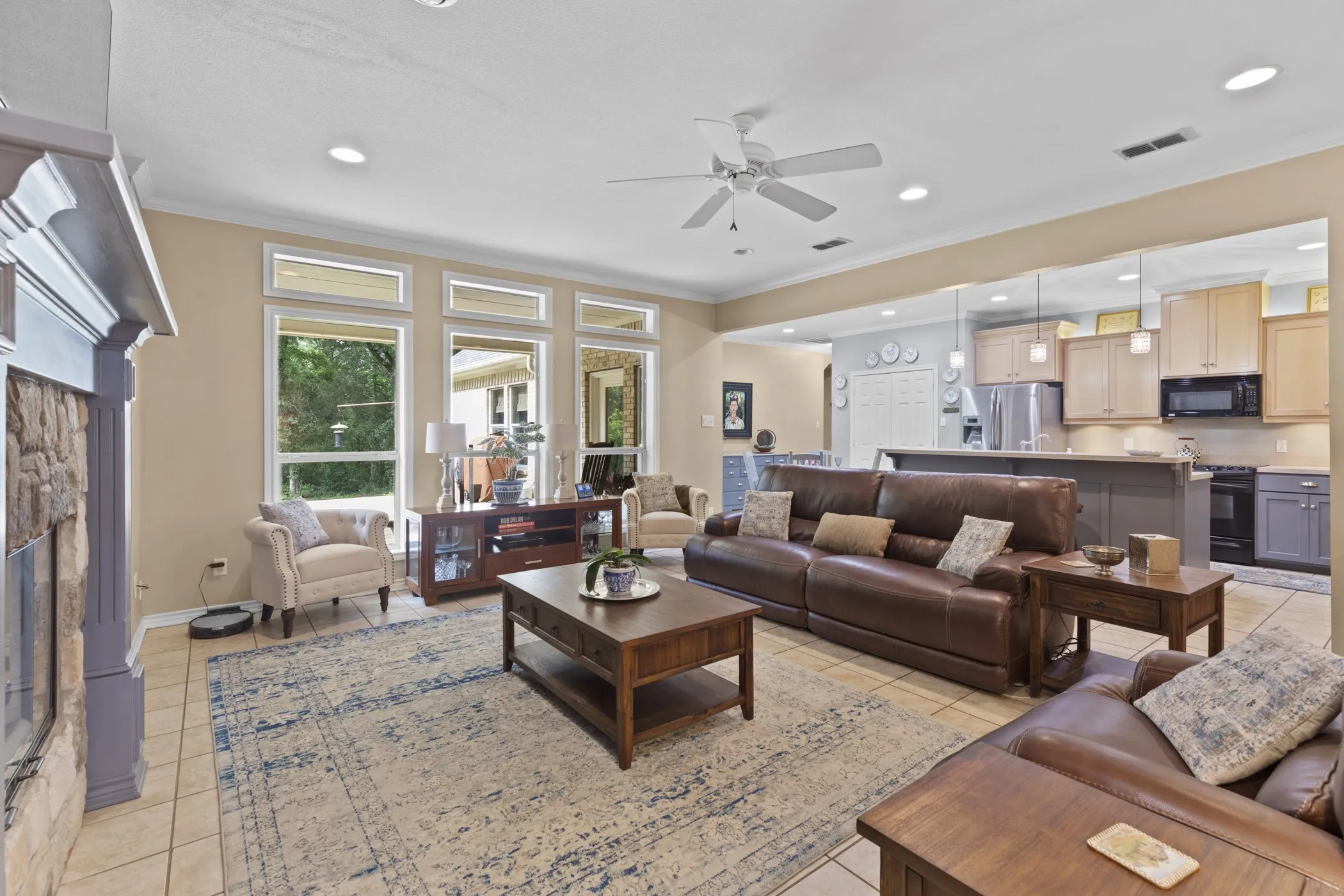 Spacious living area featuring tile flooring, a stone-front fireplace with a decorative mantel, and recessed lighting