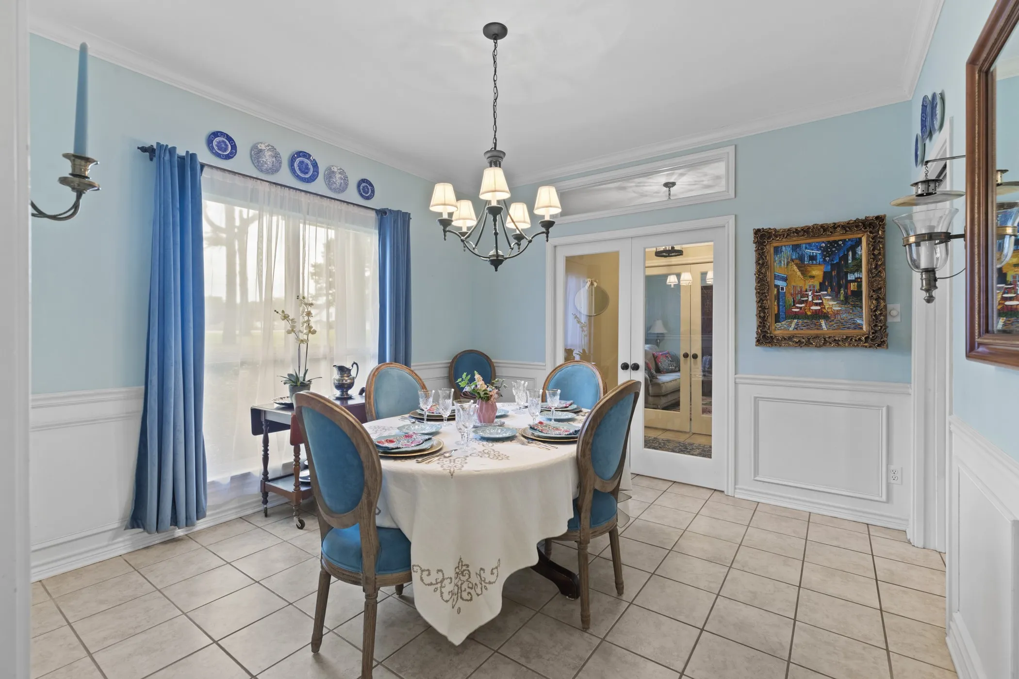 Dining area featuring light-colored tile flooring, wainscoting, and a chandelier