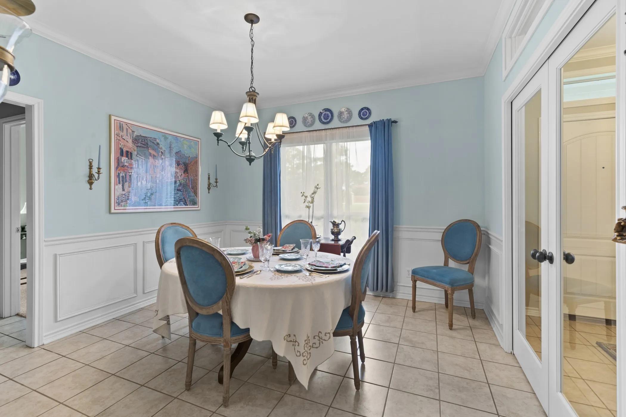 Dining space featuring wainscoting, crown molding, and a chandelier