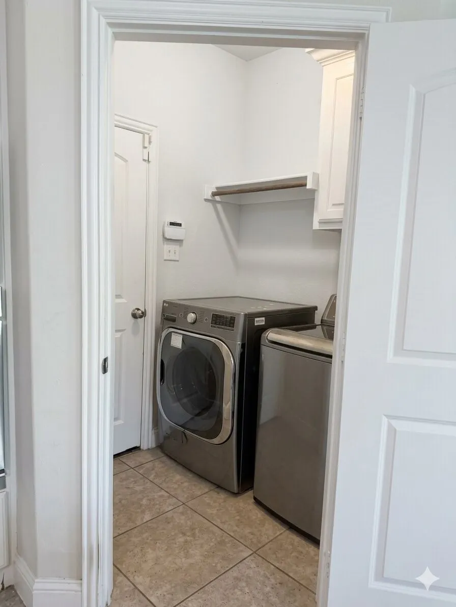 Utility area featuring neutral-toned tile flooring, light wall paint, a built-in white cabinet, and an integrated shelf with a hanging rod